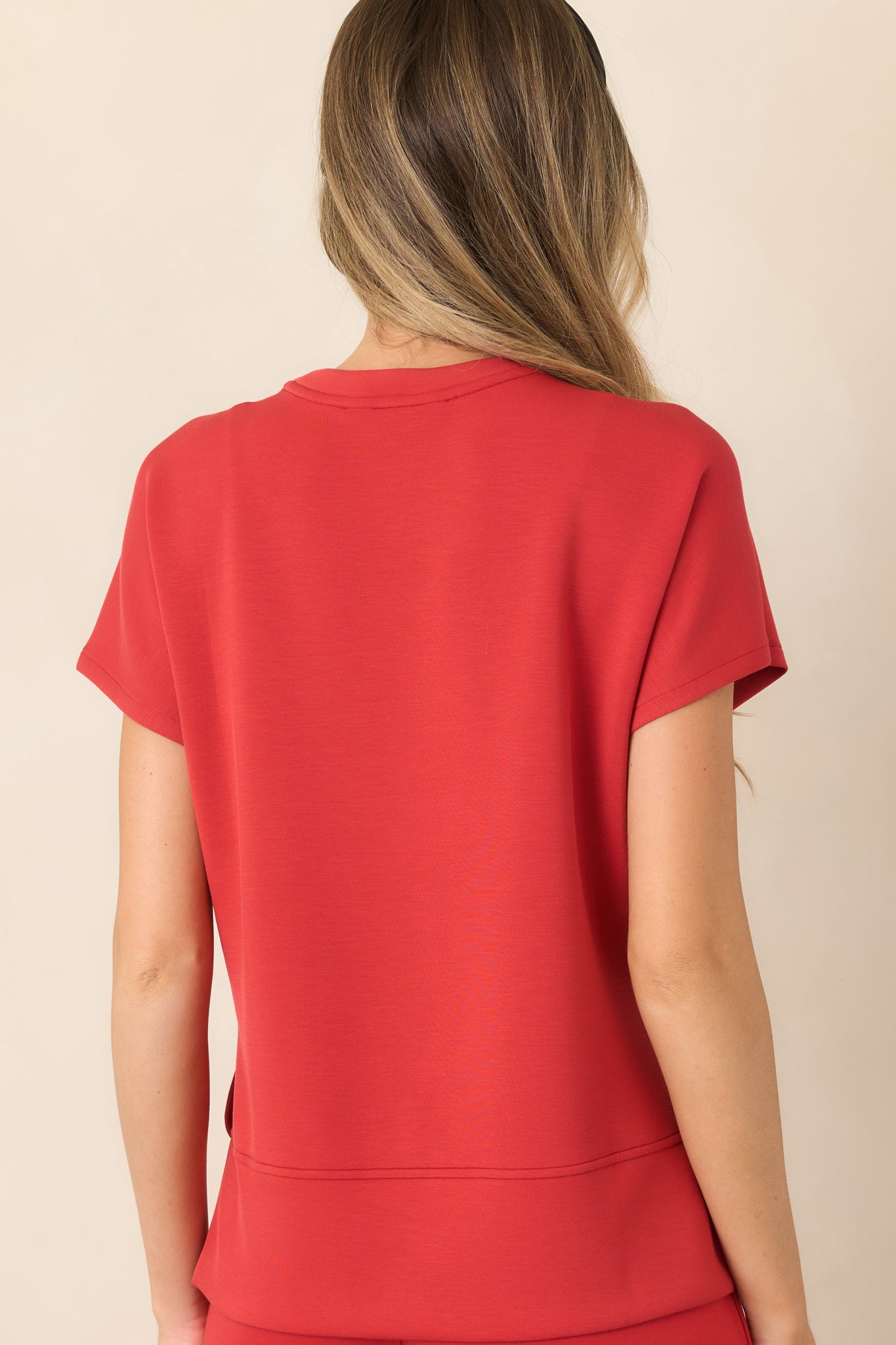 Rear view of the four-way stretch top showcasing its longer high-low hem, side slits, and softly draped silhouette.