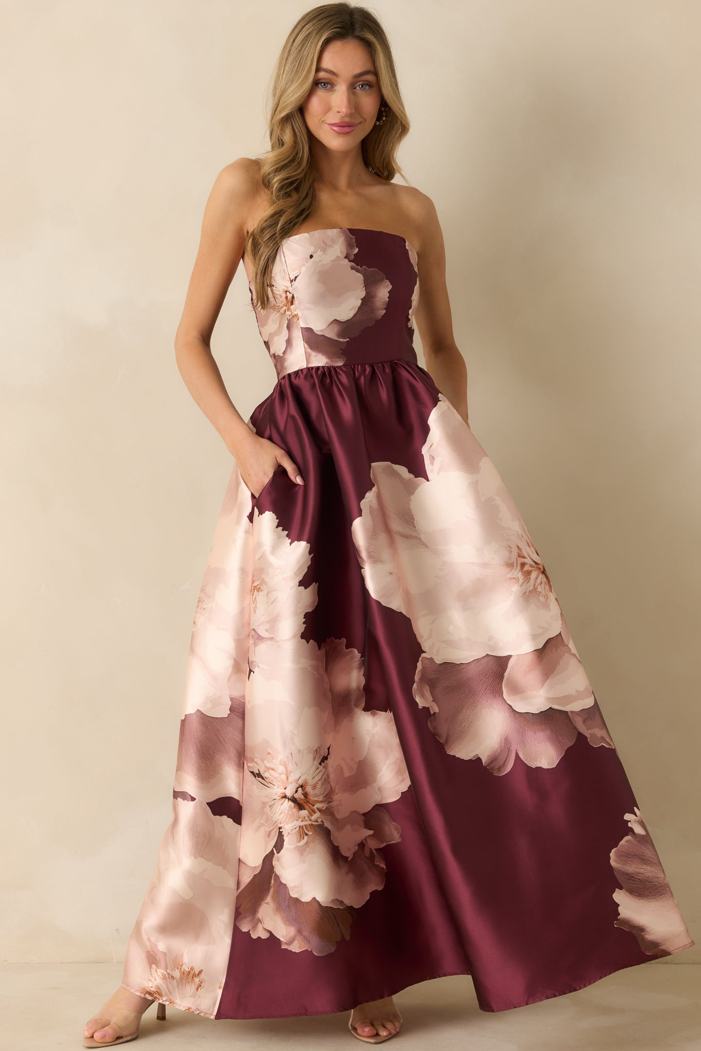 Front angled view of the burgundy satin floral maxi dress showing the smooth, flowy silhouette and side pocket placement.