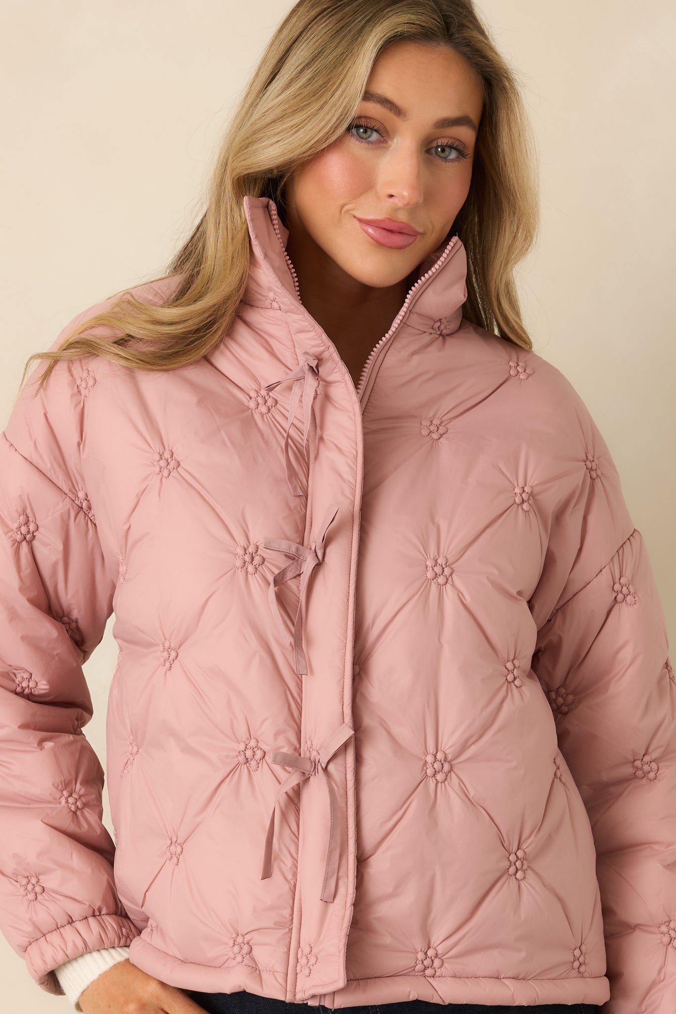 Front-focused crop emphasizing the stitched quilt pattern and soft fabric texture of the blush pink jacket.
