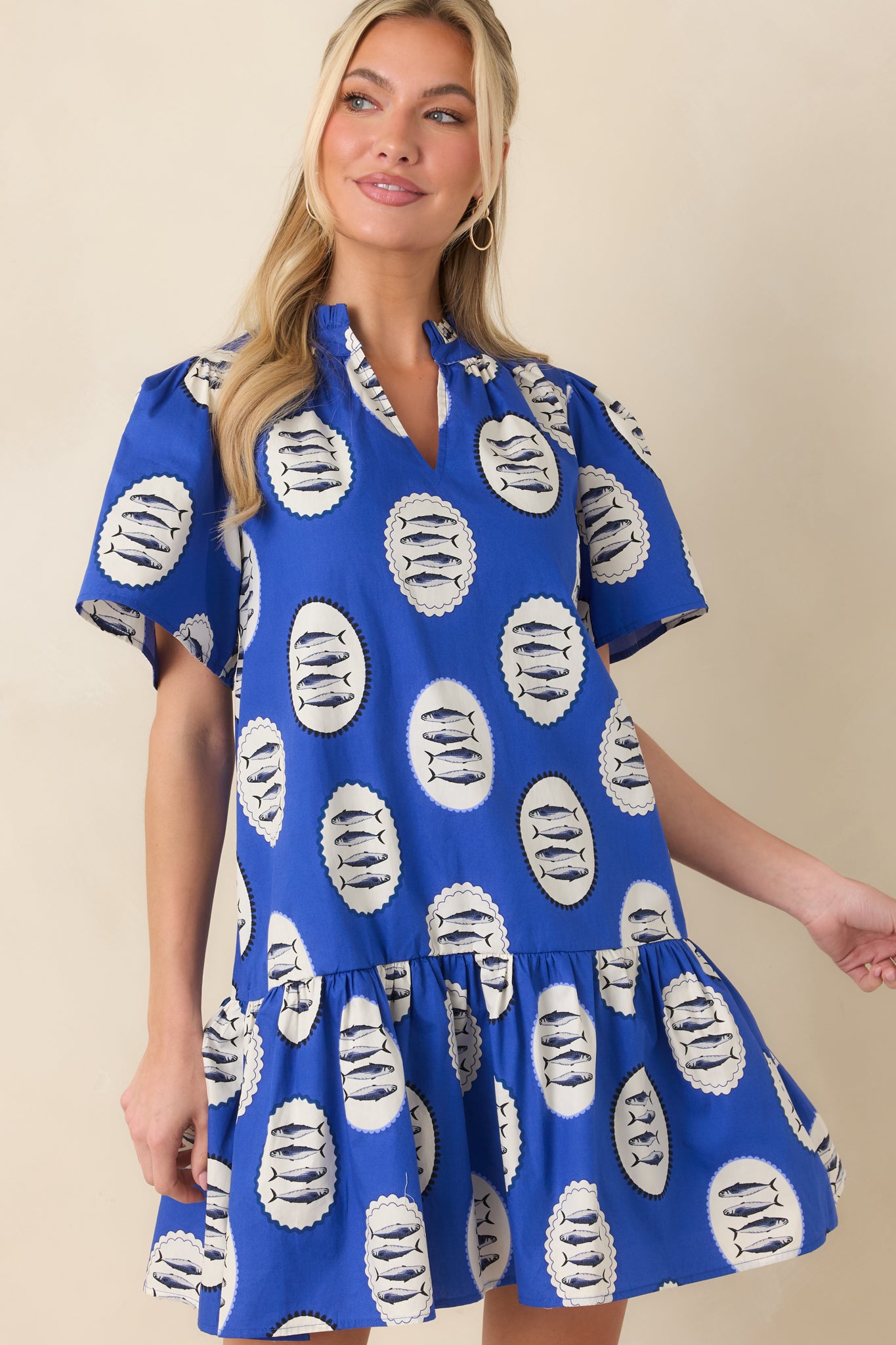 Front crop highlighting the bold fish pattern and relaxed silhouette of the blue tiered mini dress.