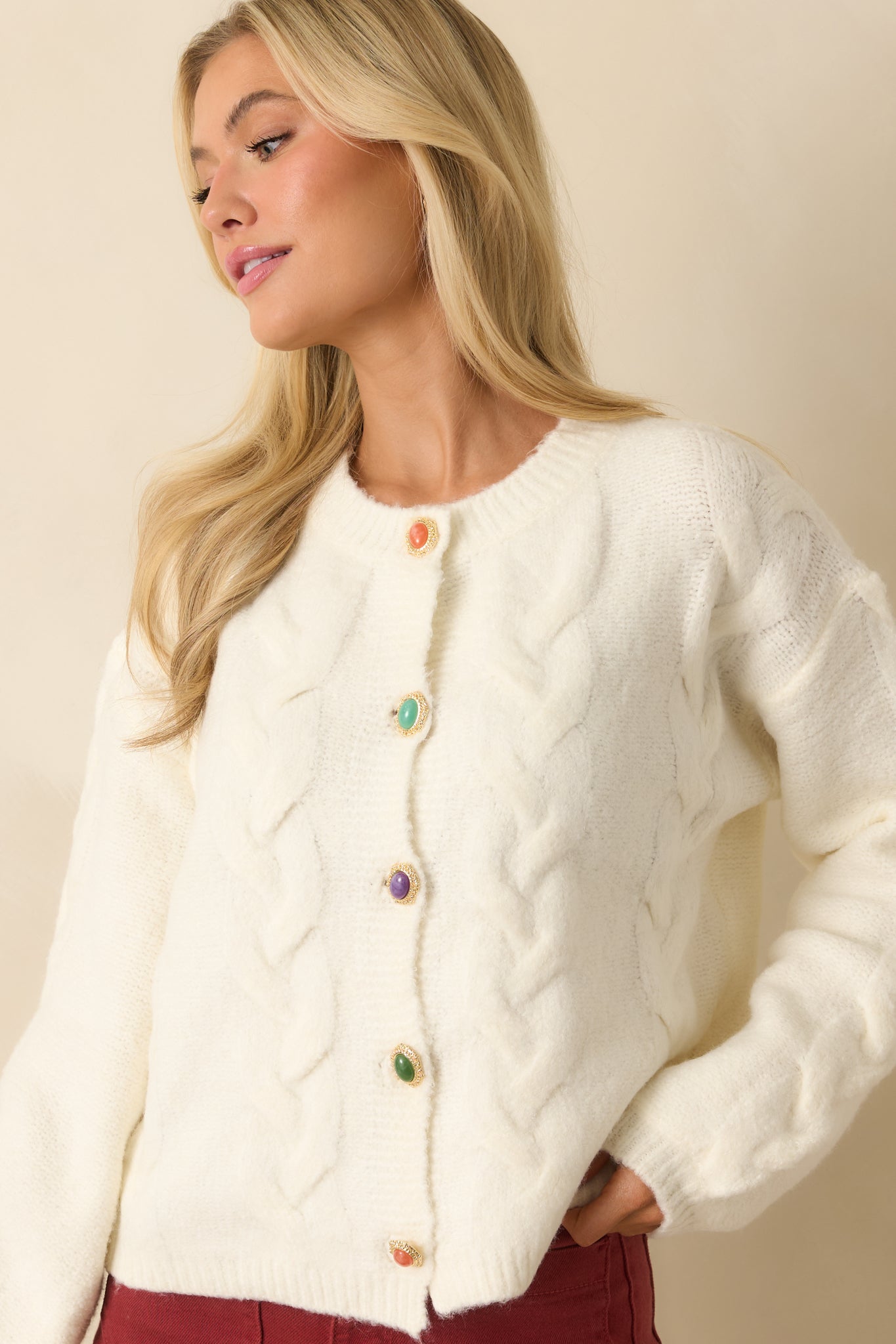 Front-focused crop highlighting ribbed trim and long sleeves of the ivory knit cardigan.