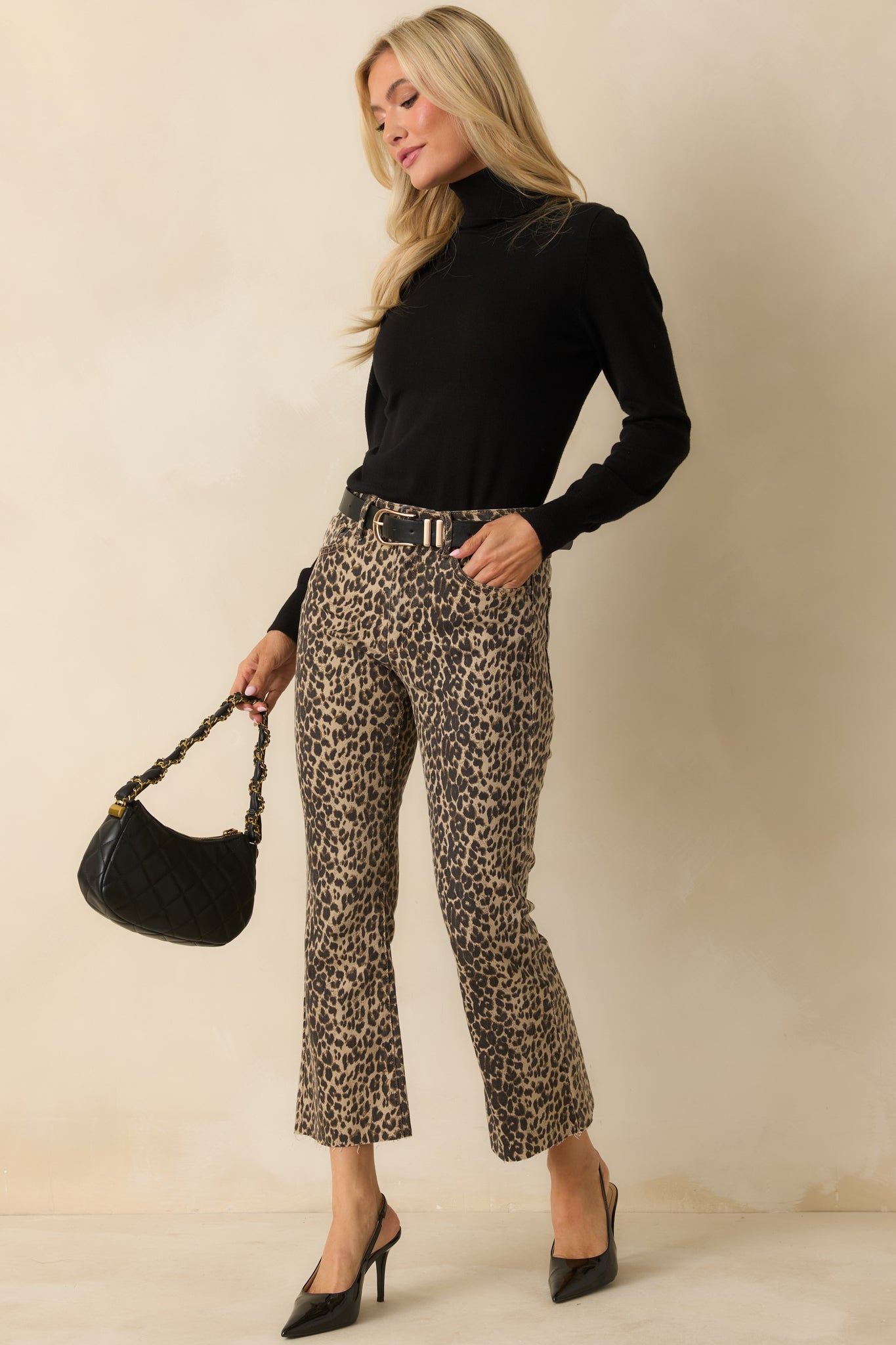 Front view of cropped flare pants highlighting the bold leopard pattern, belt loops, and relaxed fit.