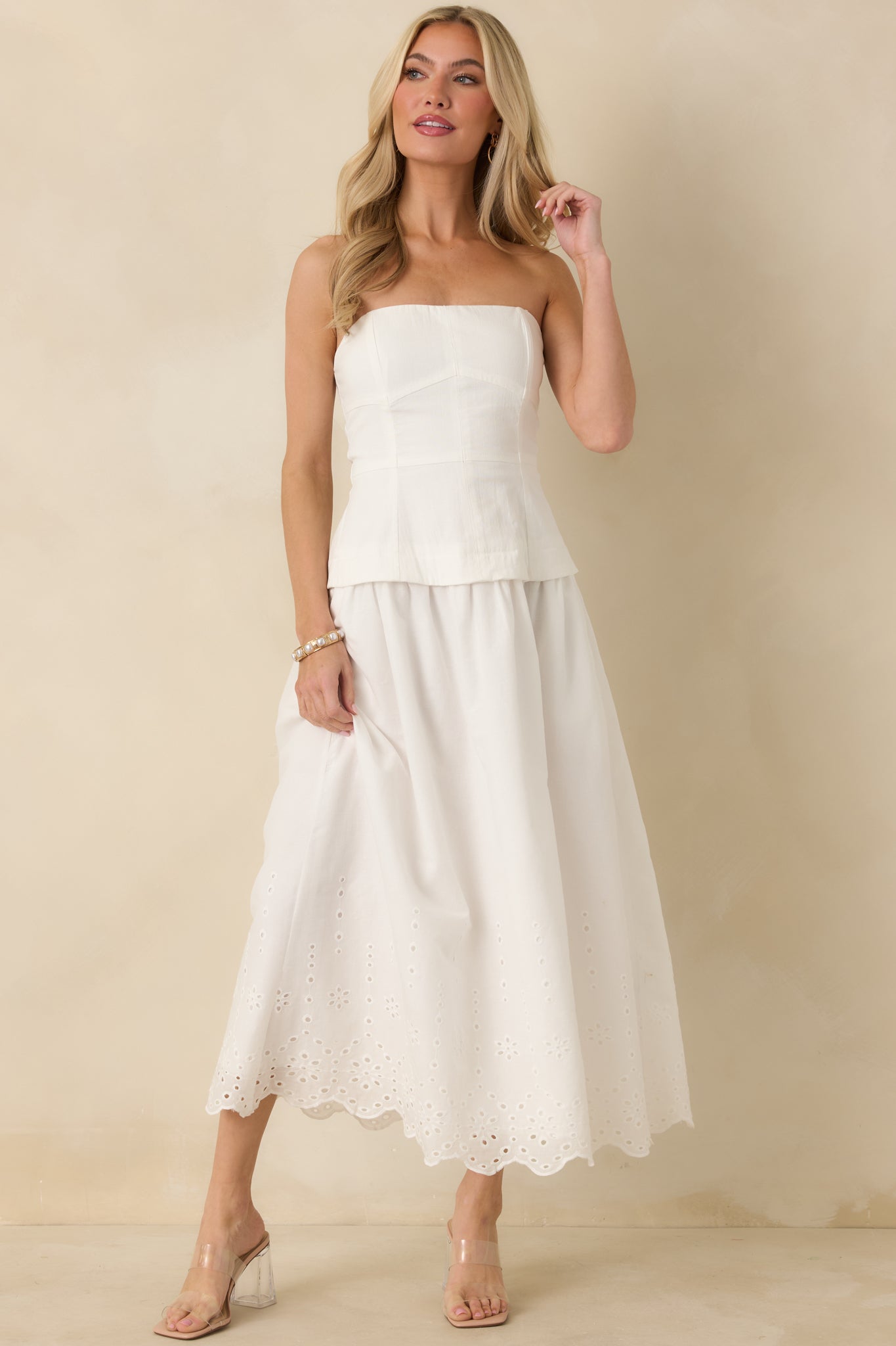 Front-facing angle highlighting the strapless structured bodice and clean seam detailing flowing into a lightweight midi skirt with embroidered eyelet trim.