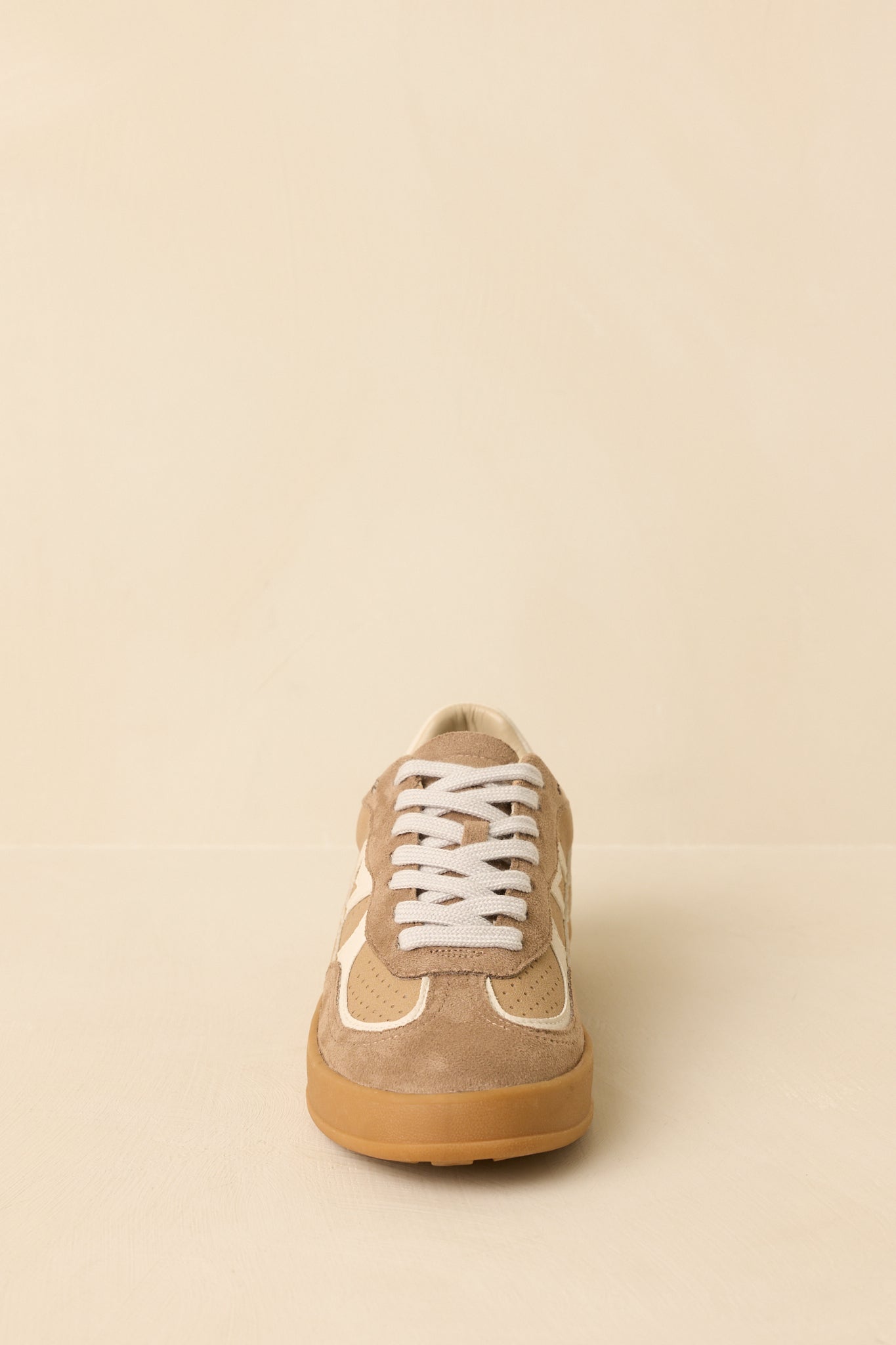 Front-facing view of tan lace-up sneakers against a beige background highlighting the mixed faux leather and suede upper.