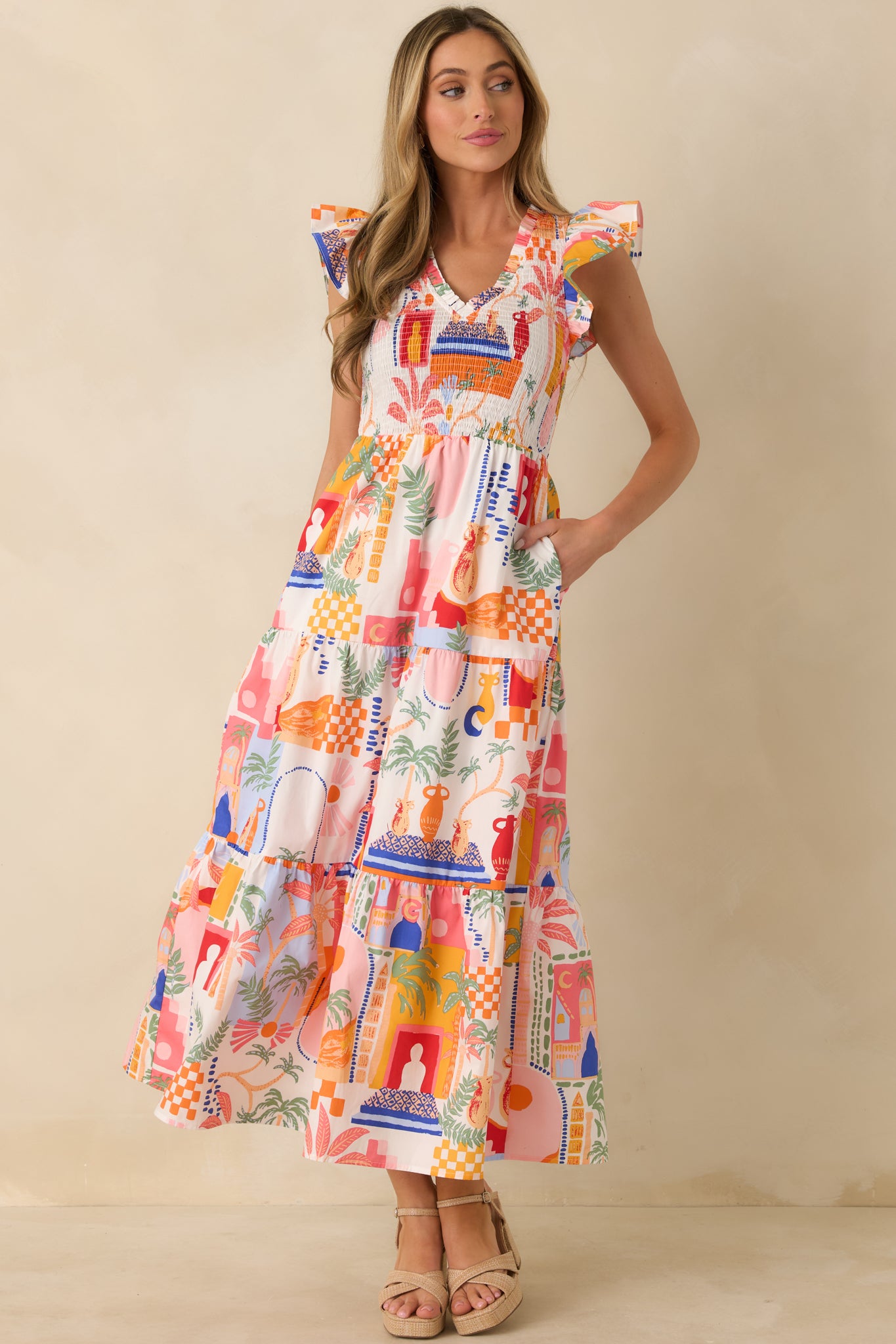 Front-facing view emphasizing the flutter sleeves, vibrant orange and pink pattern, and tiered skirt movement.