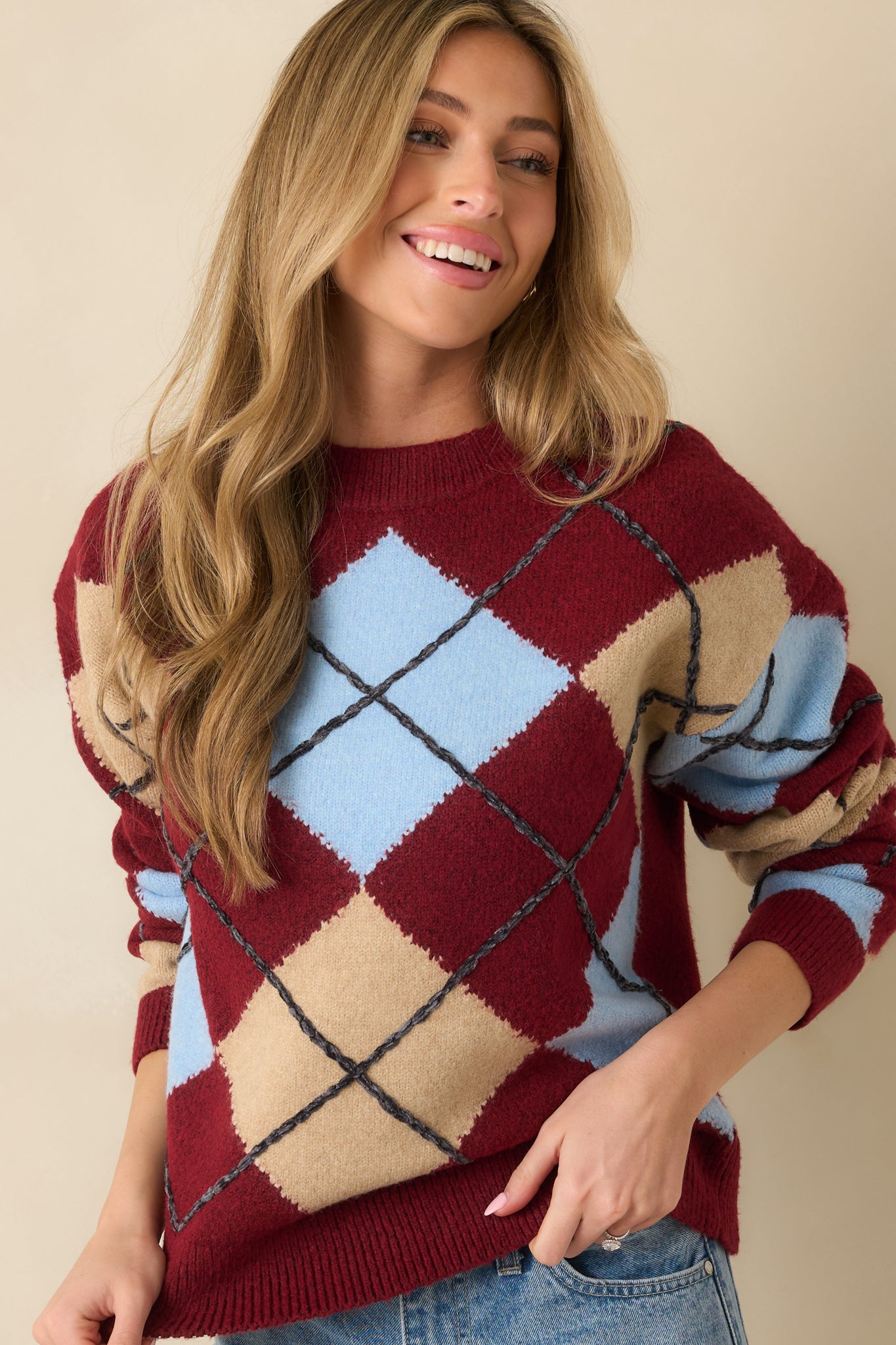 Front view of long-sleeve argyle sweater emphasizing pattern and ribbed cuffs.