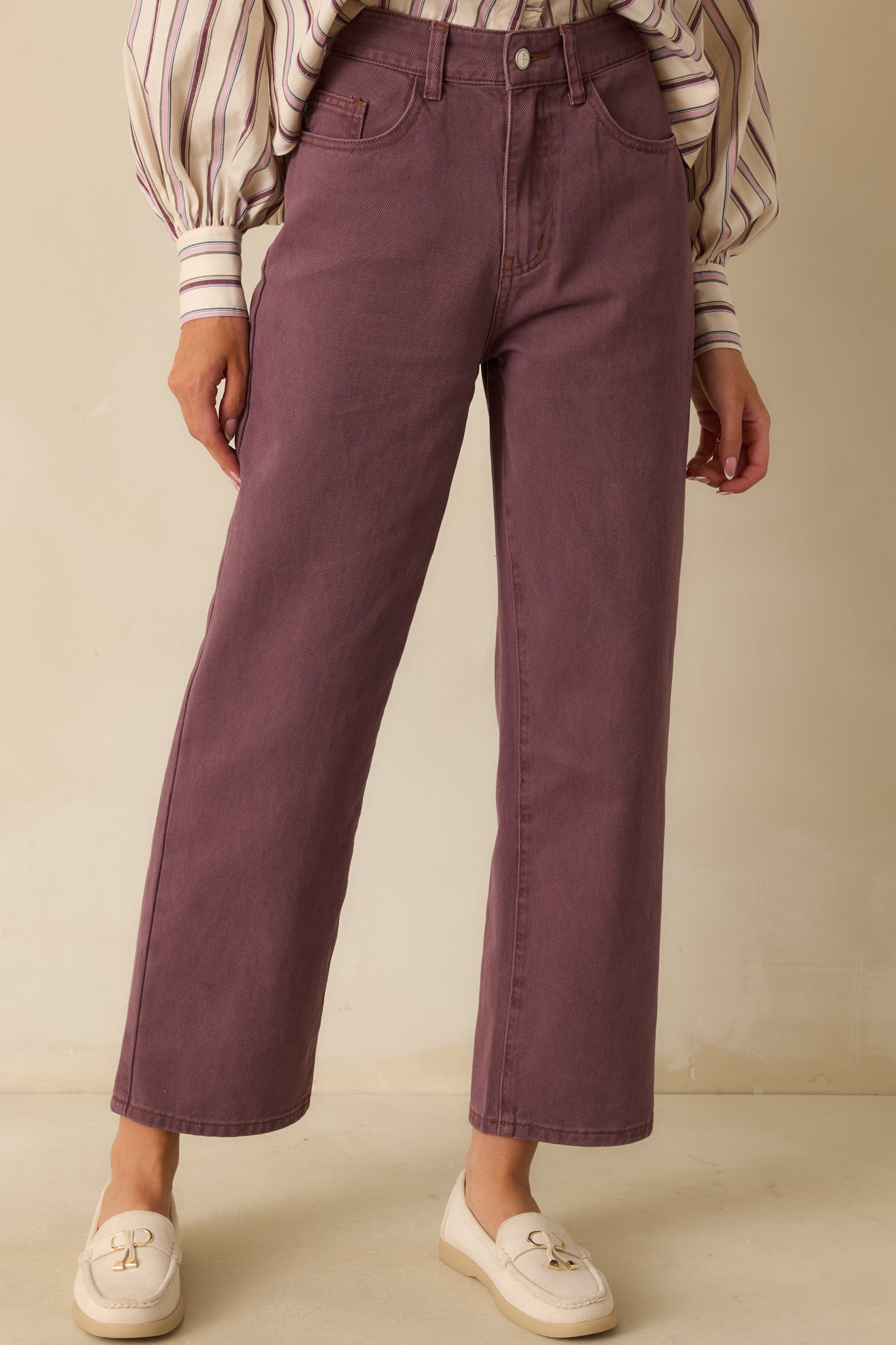 Detail of the upper front panel of the violet jeans, emphasizing the fabric texture and tailored waist.