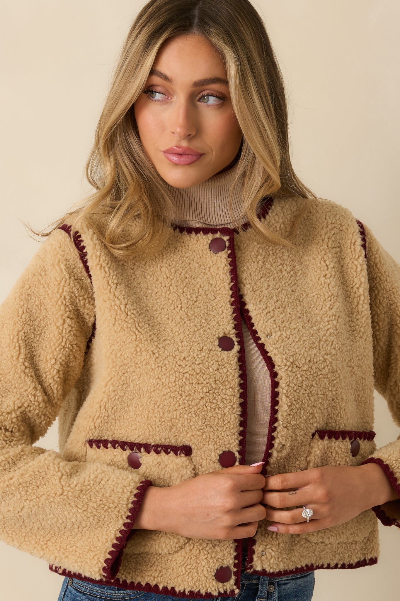 Front patch pocket outlined with burgundy stitching on the plush sherpa surface.