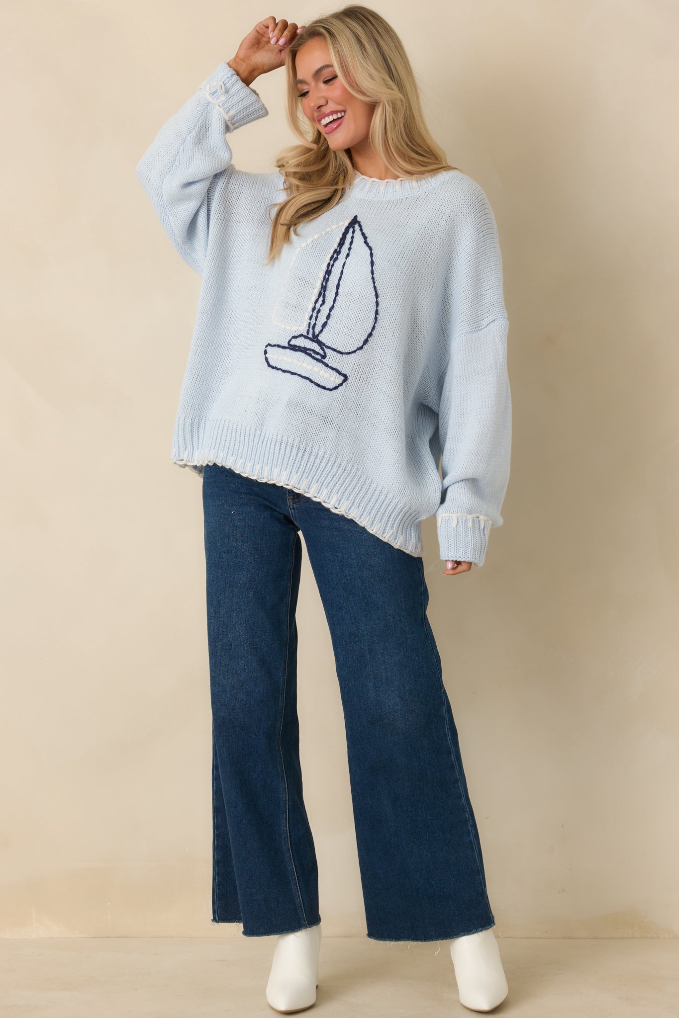 Angled front perspective highlighting the ribbed trim at the neckline, cuffs, and hem of the light blue sweater.