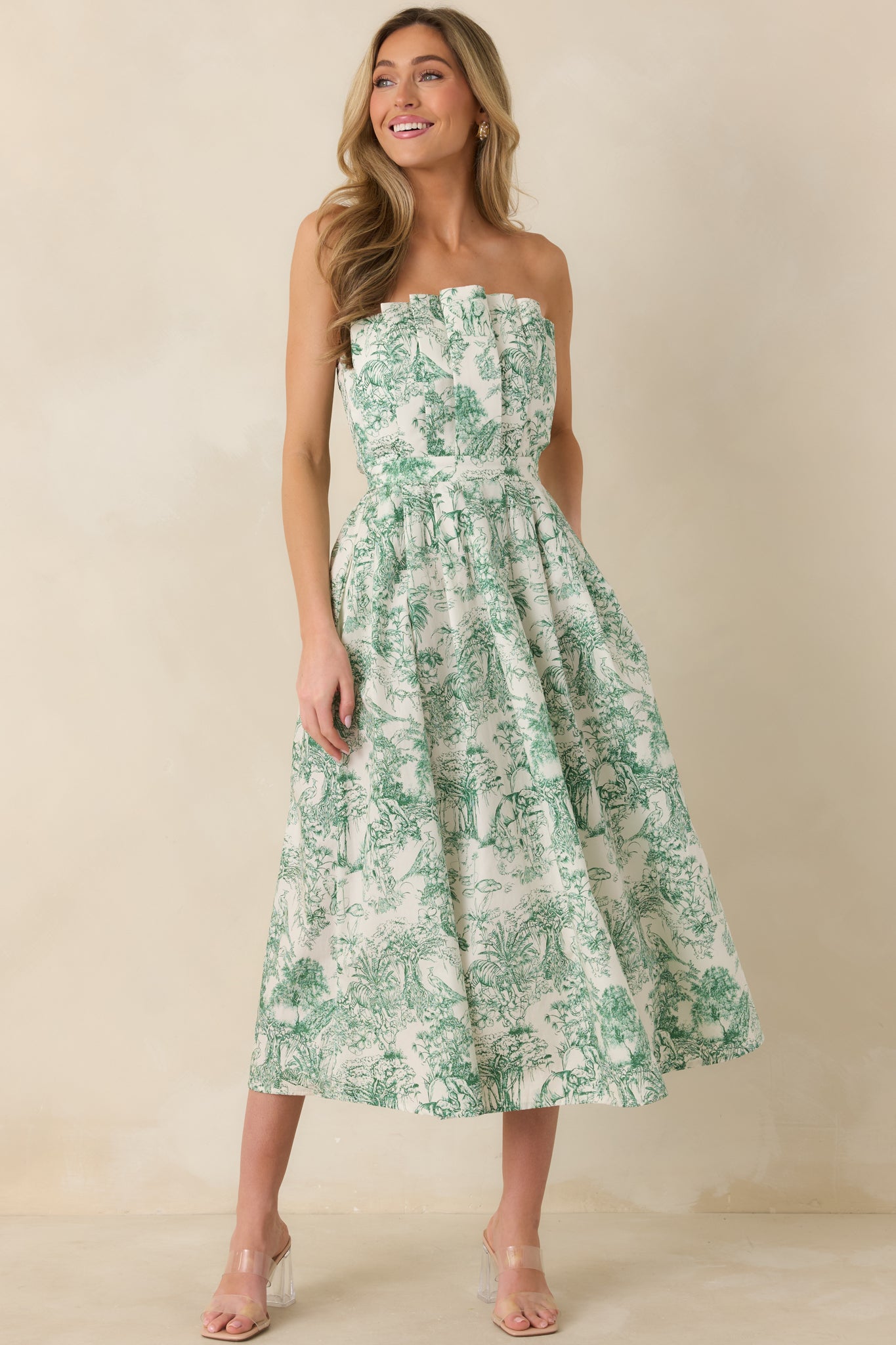 Front-facing shot of green toile midi dress emphasizing pleated bodice and refined strapless neckline.