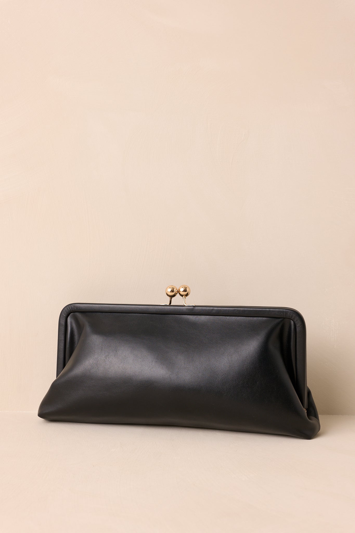 Front view of the black clutch showing its structured frame silhouette and gold-tone kiss-lock closure.