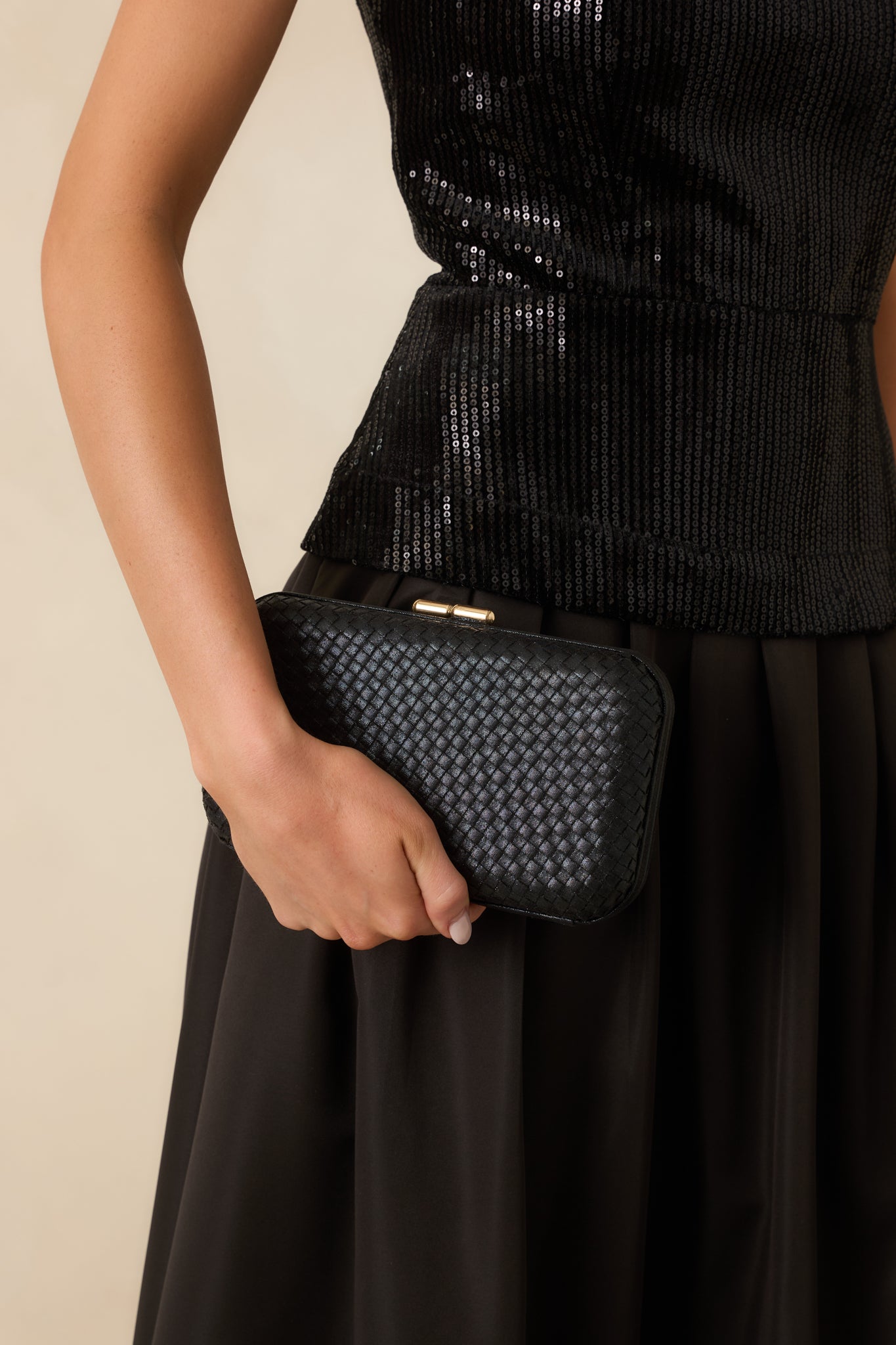 Front view of a black rectangular clutch featuring a woven hard-case design, rounded edges, and a top clasp closure.