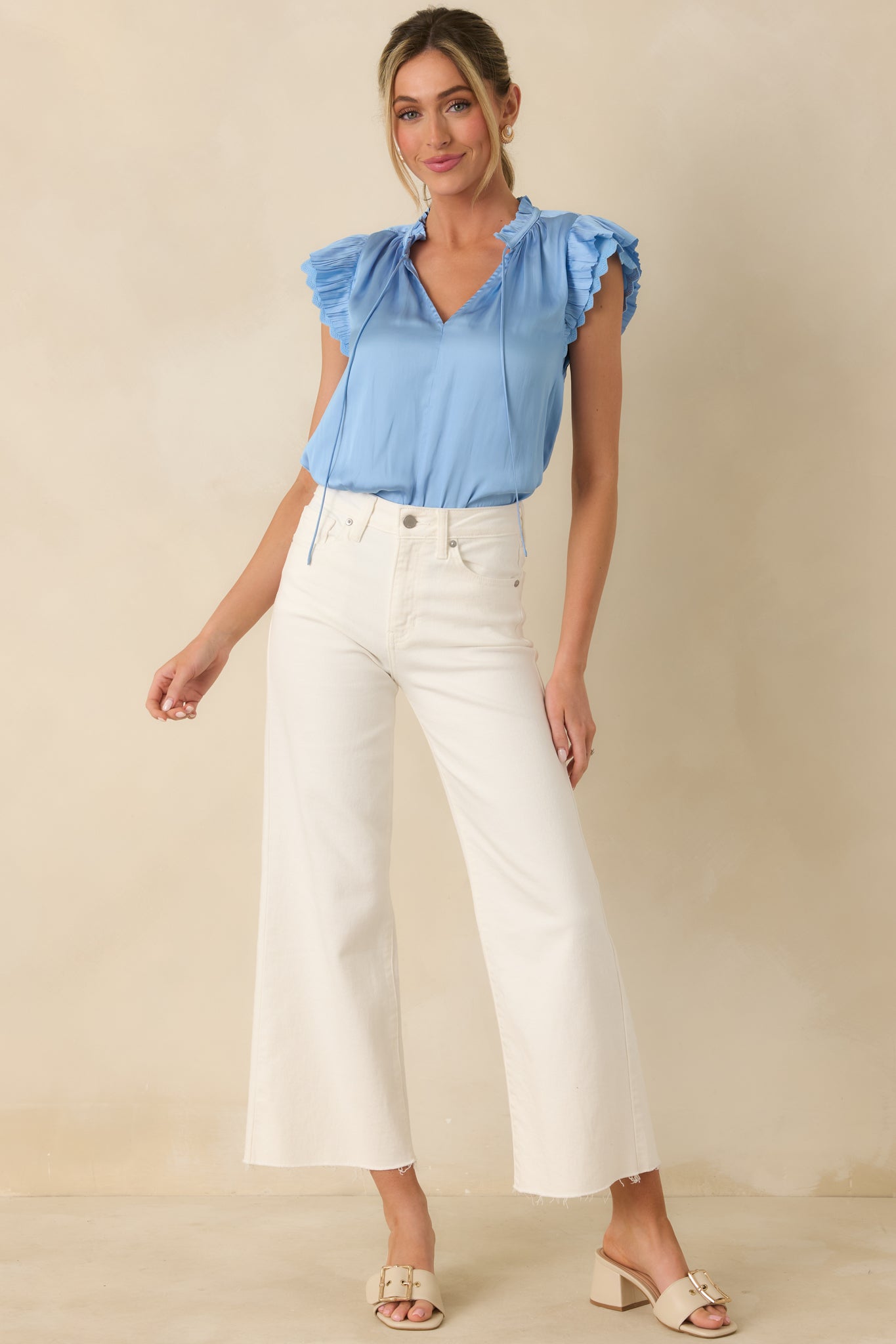 Front view of a blue blouse emphasizing the airy drape and delicate lace trim along the flutter sleeves.