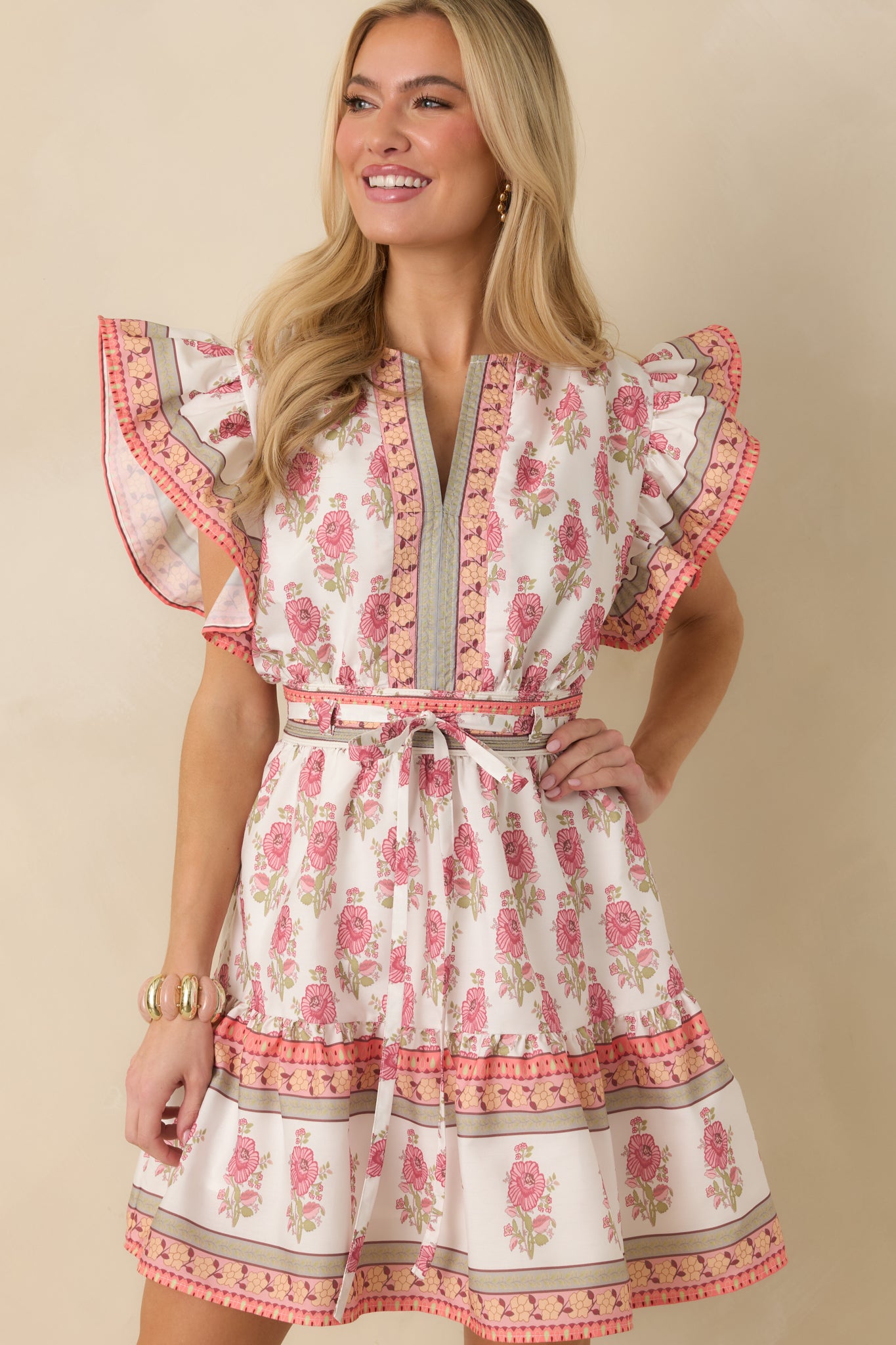 Cropped front view of the white floral dress emphasizing the V-neckline, flutter sleeves, and elastic waistband.