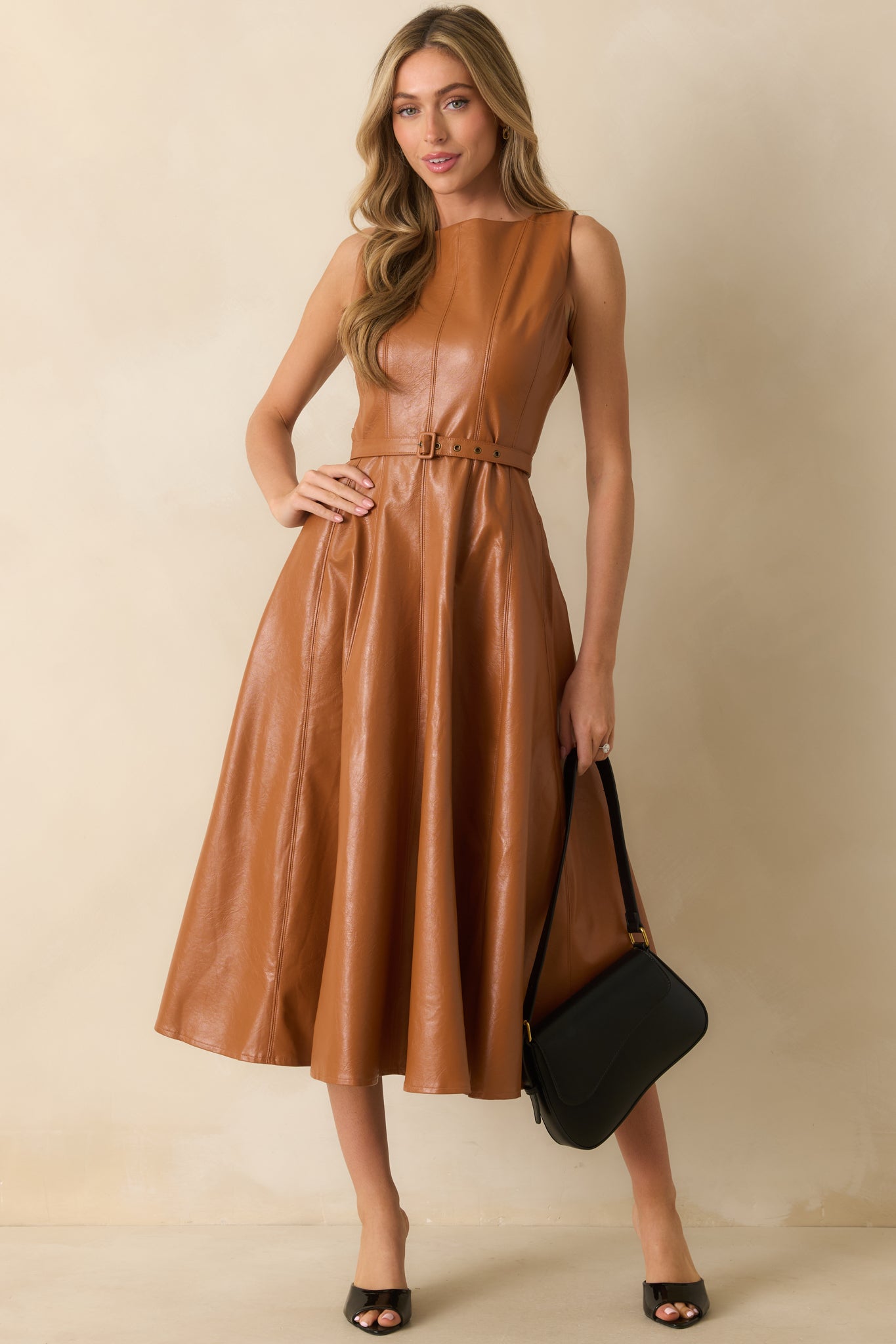 Front view of a faux leather midi dress featuring a removable belt with buckle closure and structured silhouette.