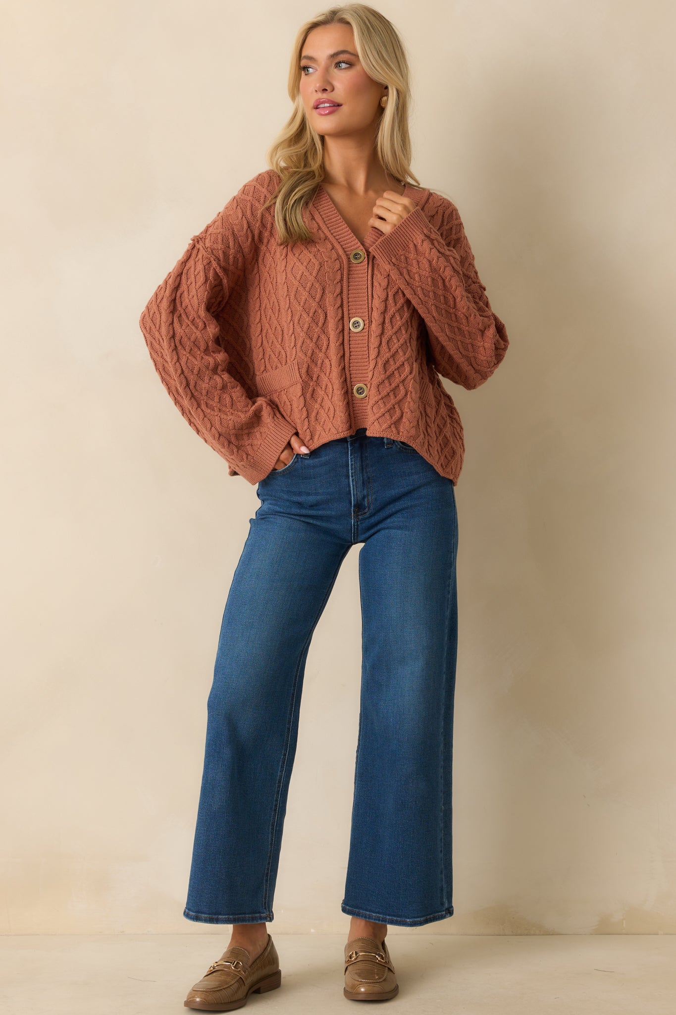 A front-facing view showing the faux patch pockets and overall cable knit pattern.