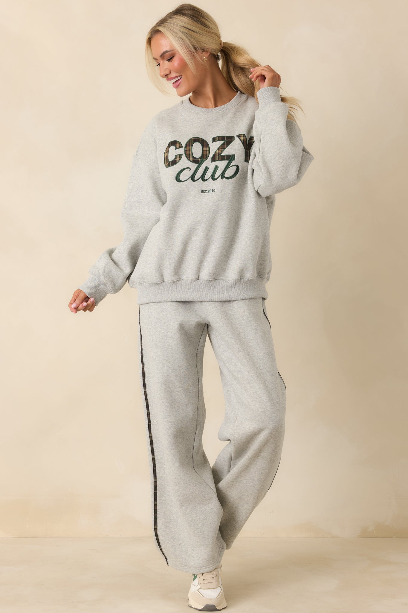 Front view of soft grey knit pants featuring contrast plaid side stripes and functional pockets.