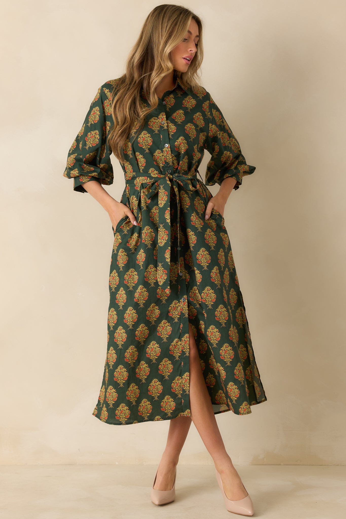 Front view of a green floral maxi dress featuring side pockets and a detachable self-tie waist belt.