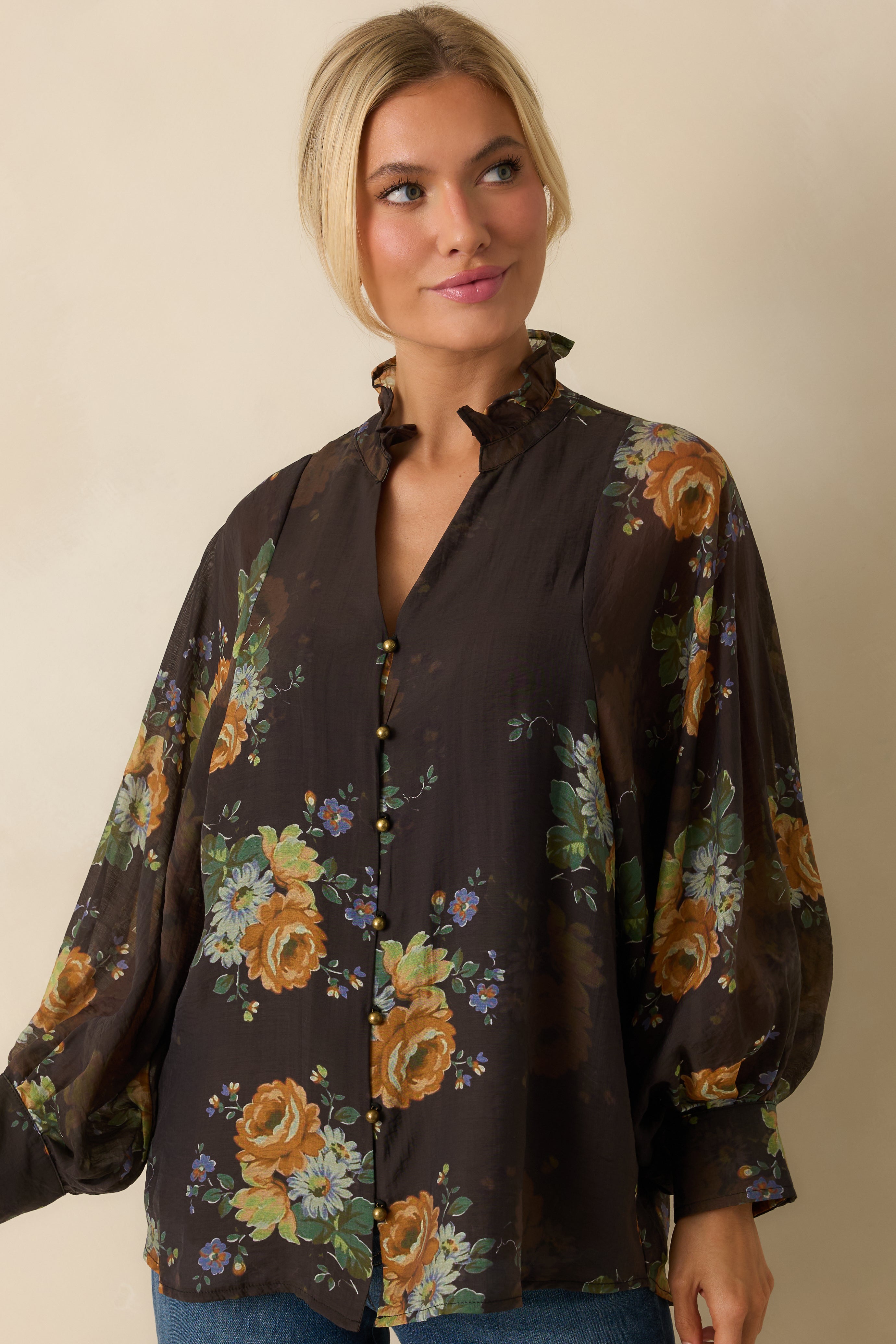 Front view highlighting the ruffled neckline and multicolor floral print on the brown blouse.