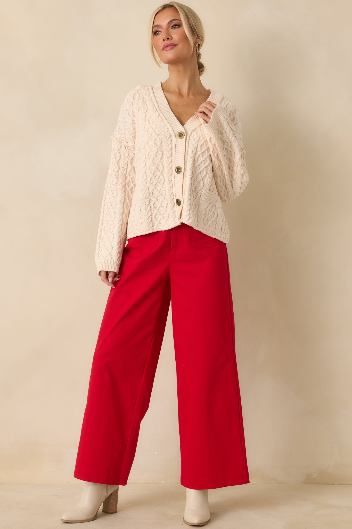 Front view of the ivory cable knit cardigan showing the relaxed fit, v-neckline, and full button-front closure.