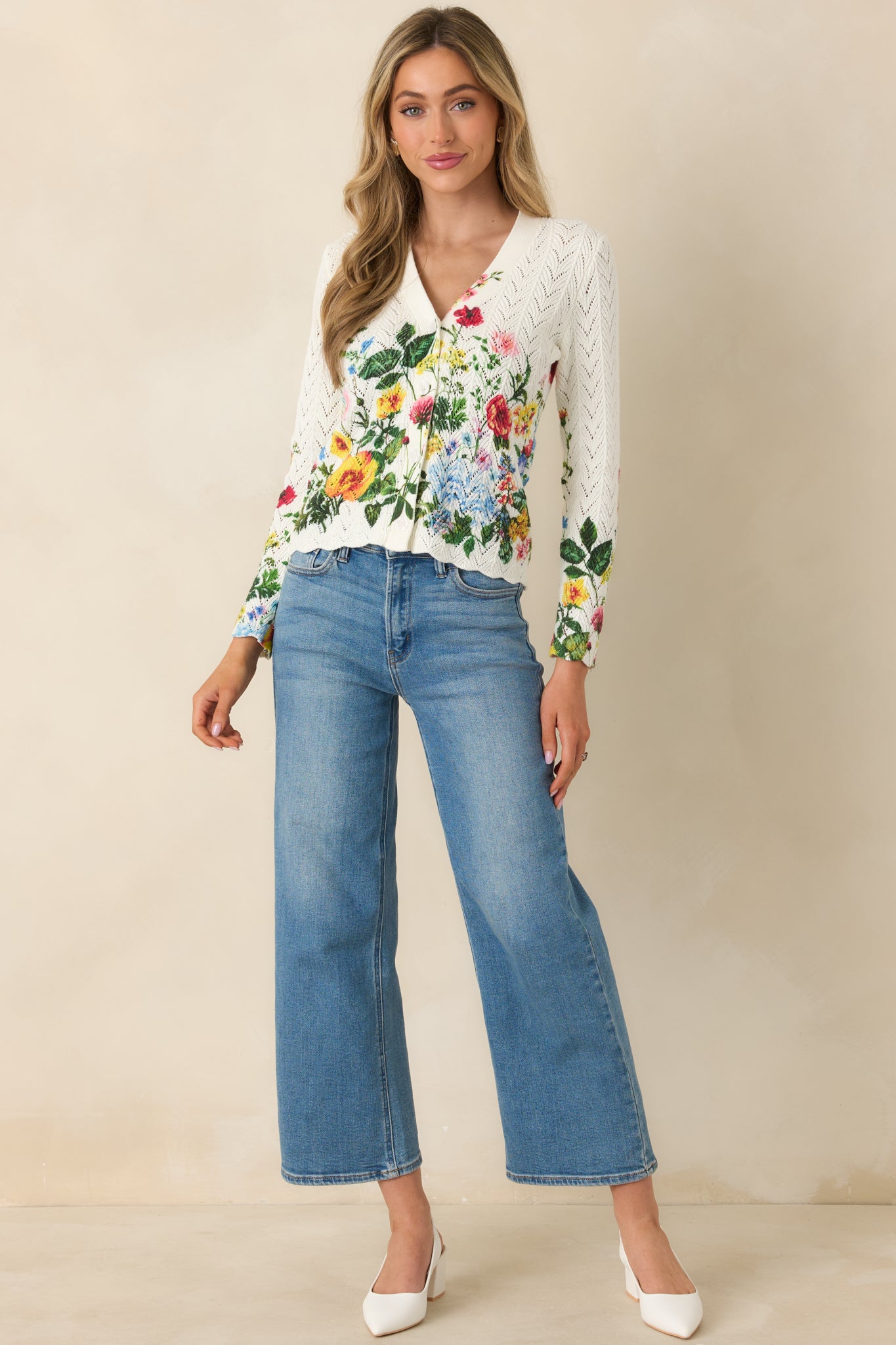 Front view of an ivory cardigan featuring allover openwork texture, fitted long sleeves, and scalloped hem detailing.