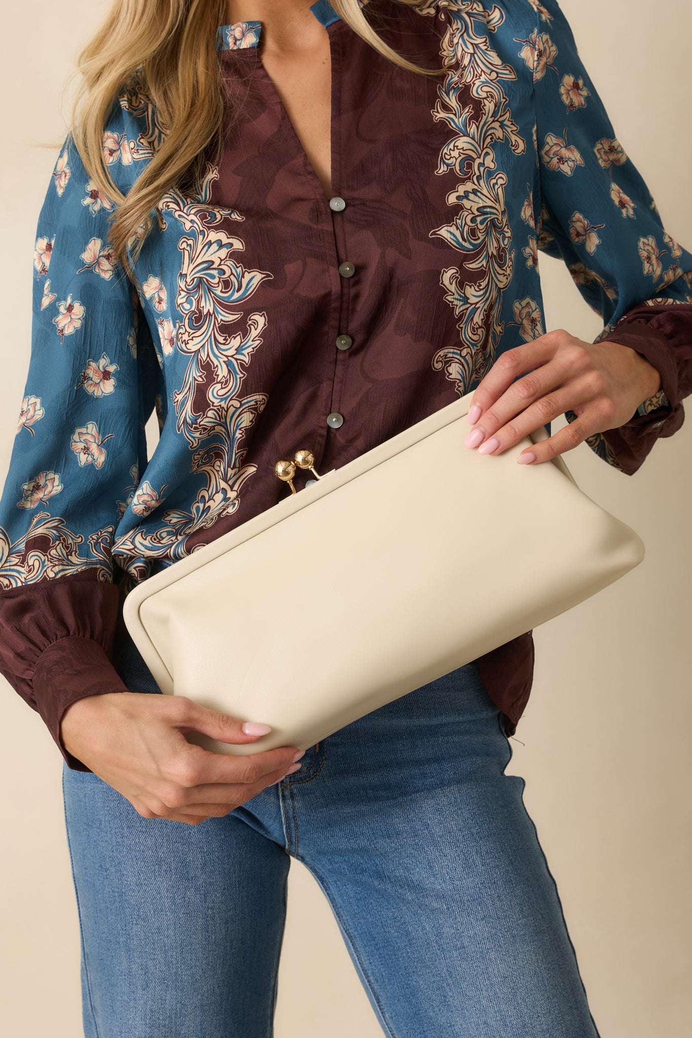 A front view of the ivory clutch featuring smooth faux leather, rectangular silhouette, and gold kiss-lock closure.