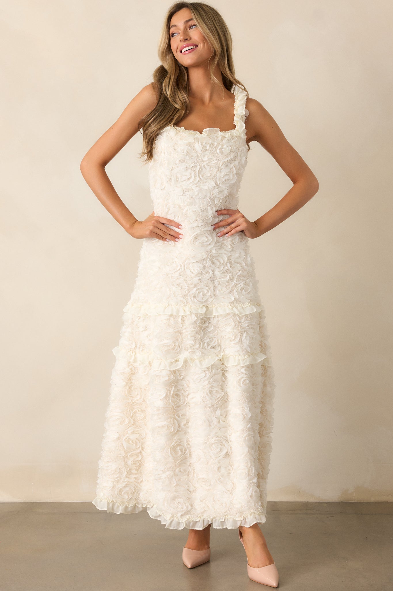 The ivory dress from a front angle, highlighting the ruffle shoulder details and the intricate floral appliques throughout.