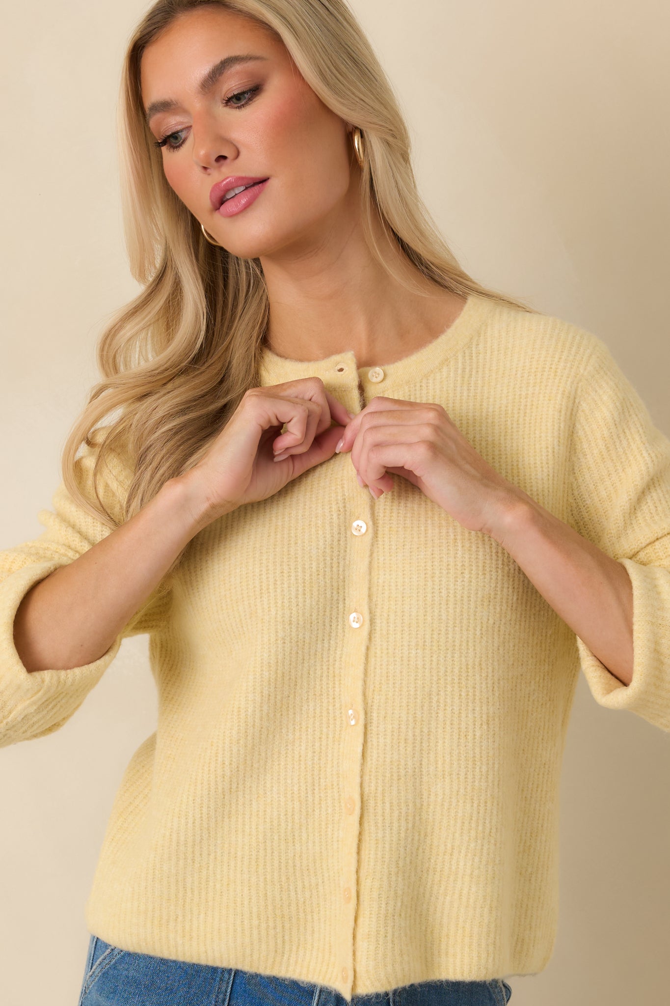 Front view of the light yellow knit showing the lightweight ribbing, smooth button placket, and long sleeves.