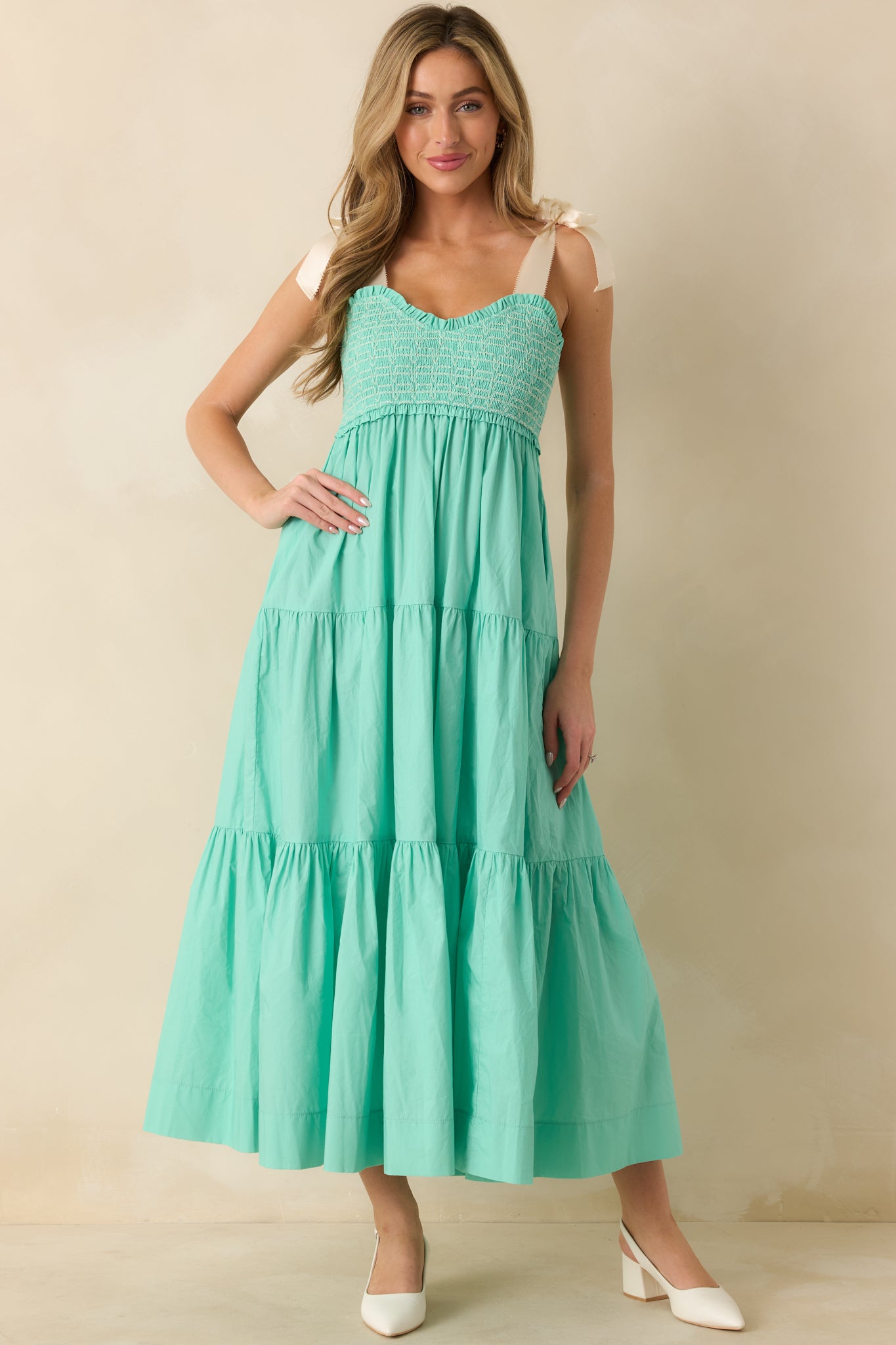 Front view of mint green midi dress featuring white embroidered smocking, self-tie bow straps, and functional side pockets.