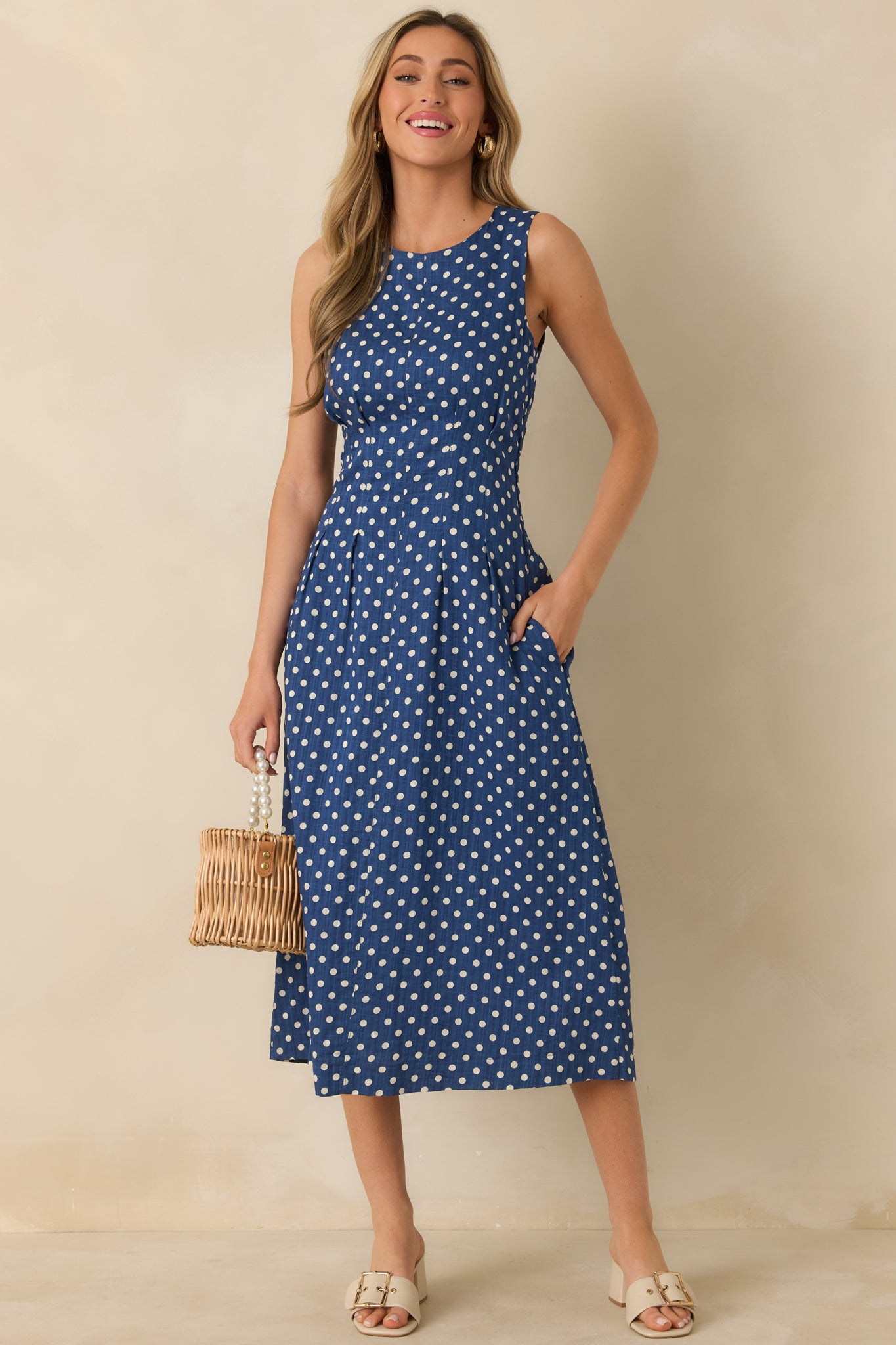 Front view of navy midi dress with white polka dots showing round neckline and flared A-line skirt.