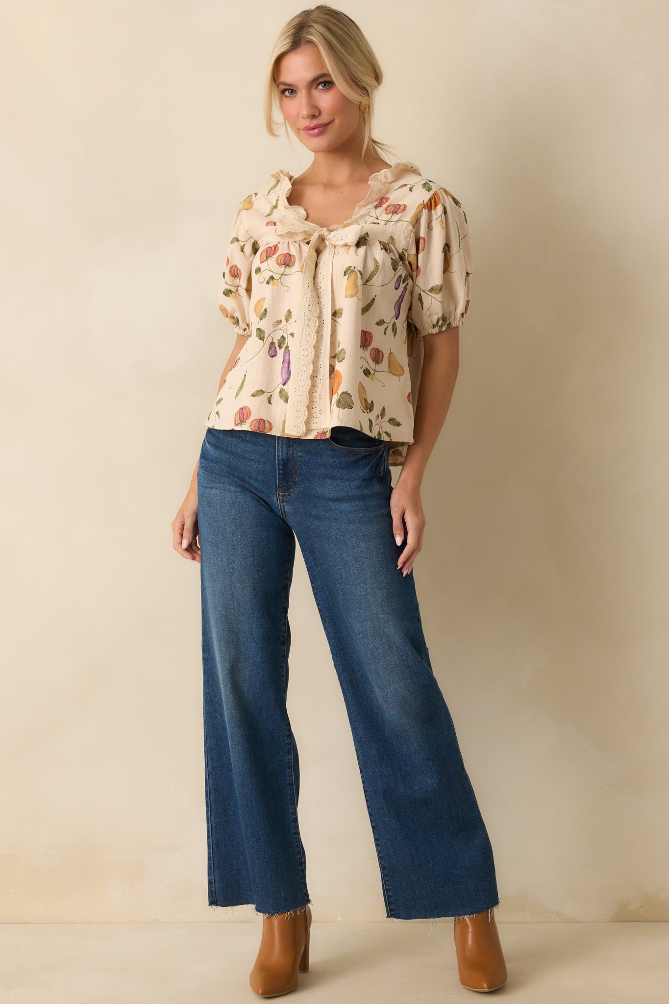 Front view of ivory blouse featuring scalloped lace trim, short puff sleeves, and tied front closure.