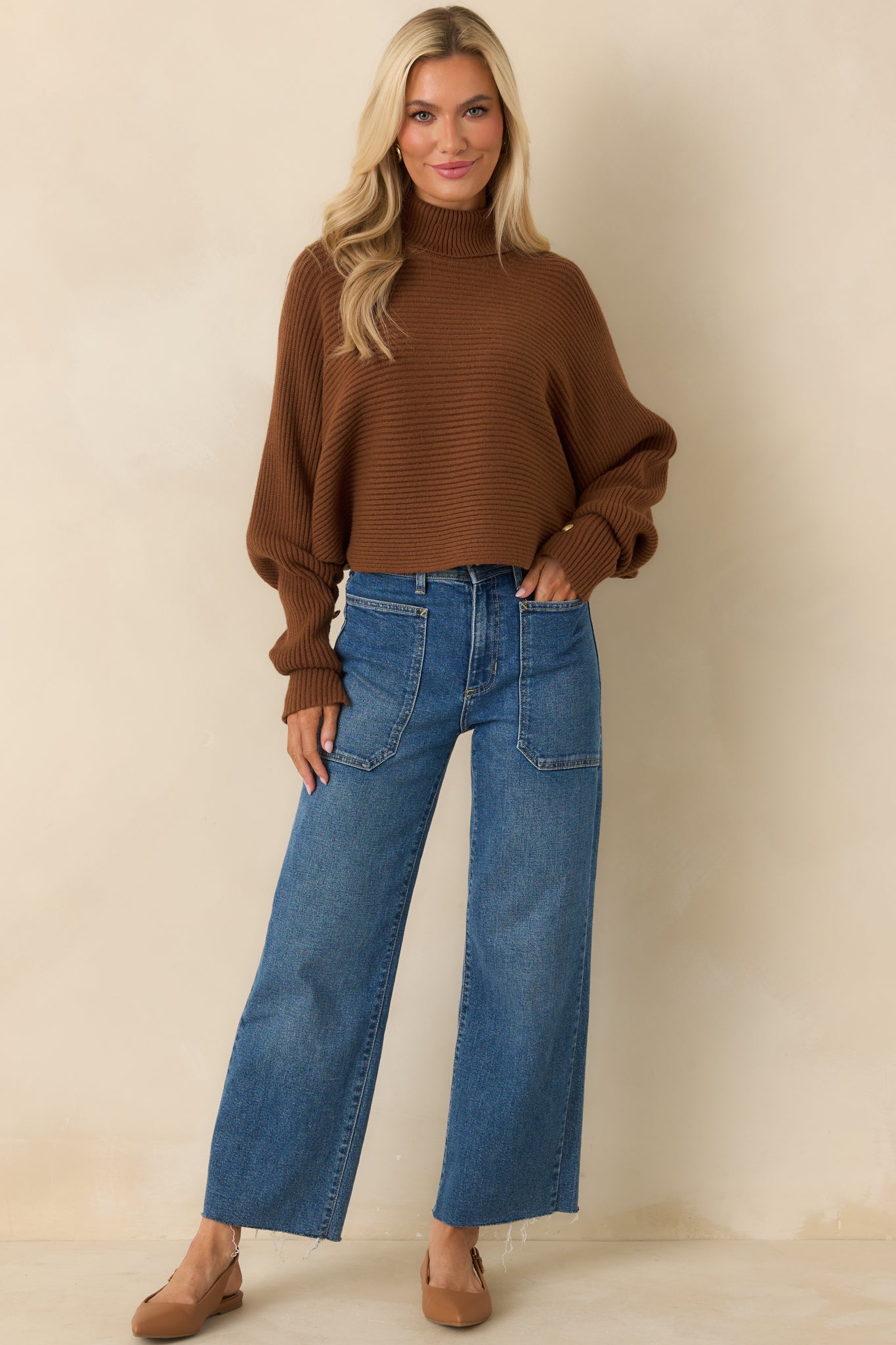 Front view of cropped brown pullover sweater with button-accented cuffs.