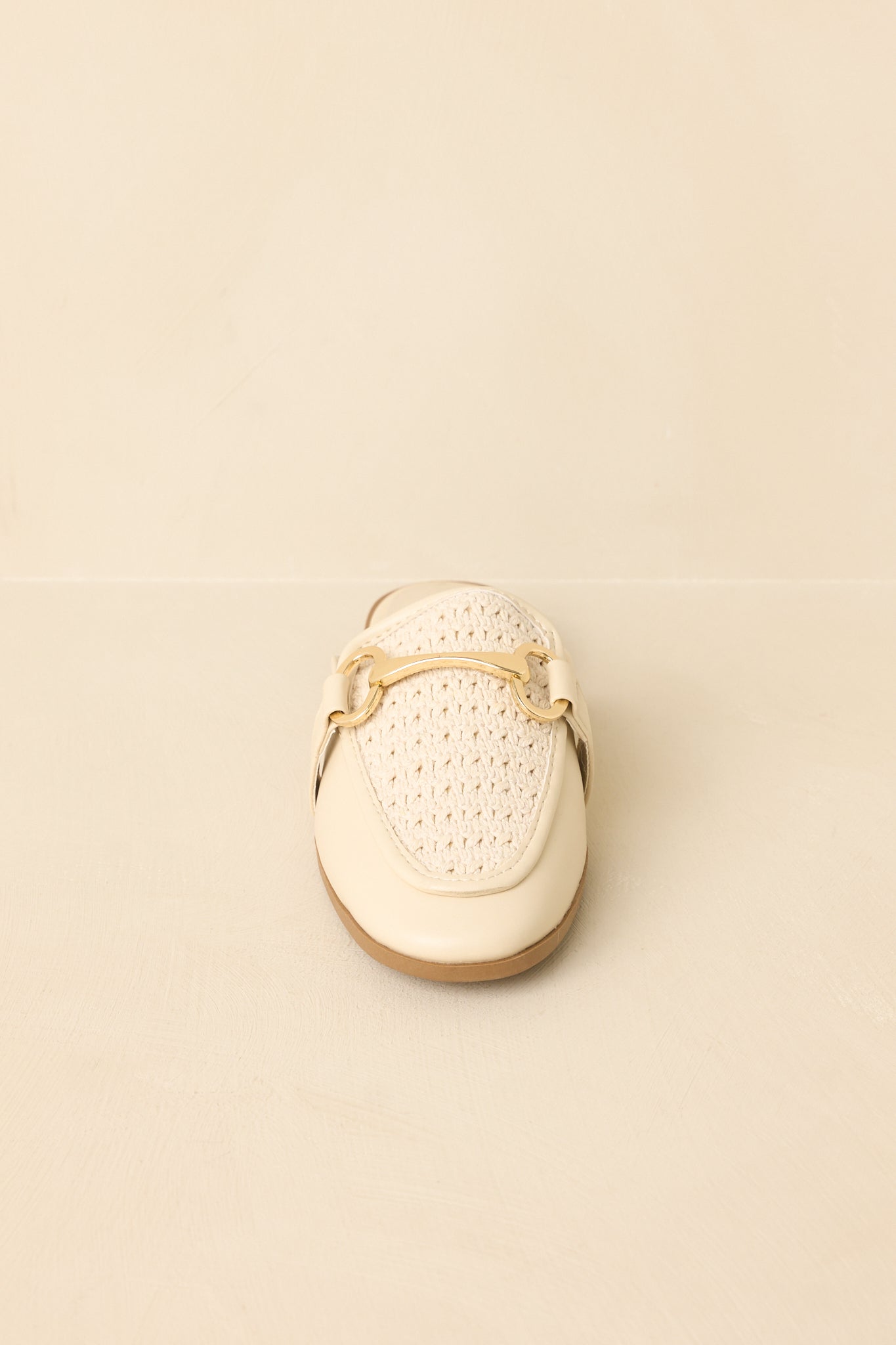 Front view of ivory faux leather loafers on a beige background showcasing the structured woven upper.