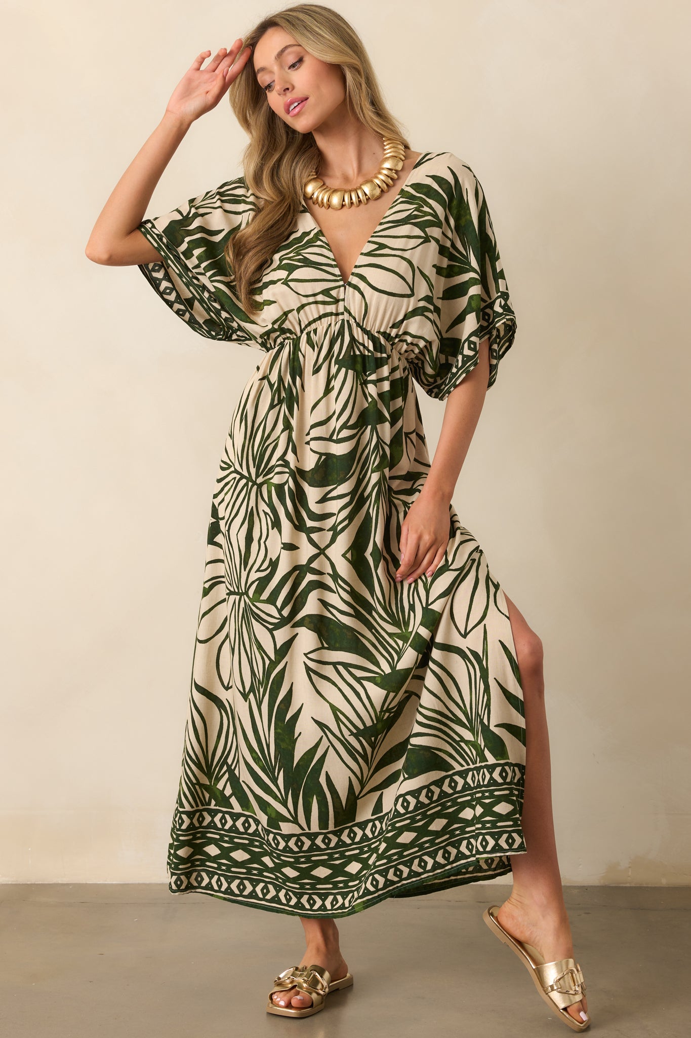 Front view of the maxi dress with a palm leaf print, deep V-neck, and short kimono sleeves, showing off the geometric accents at the bottom hem.