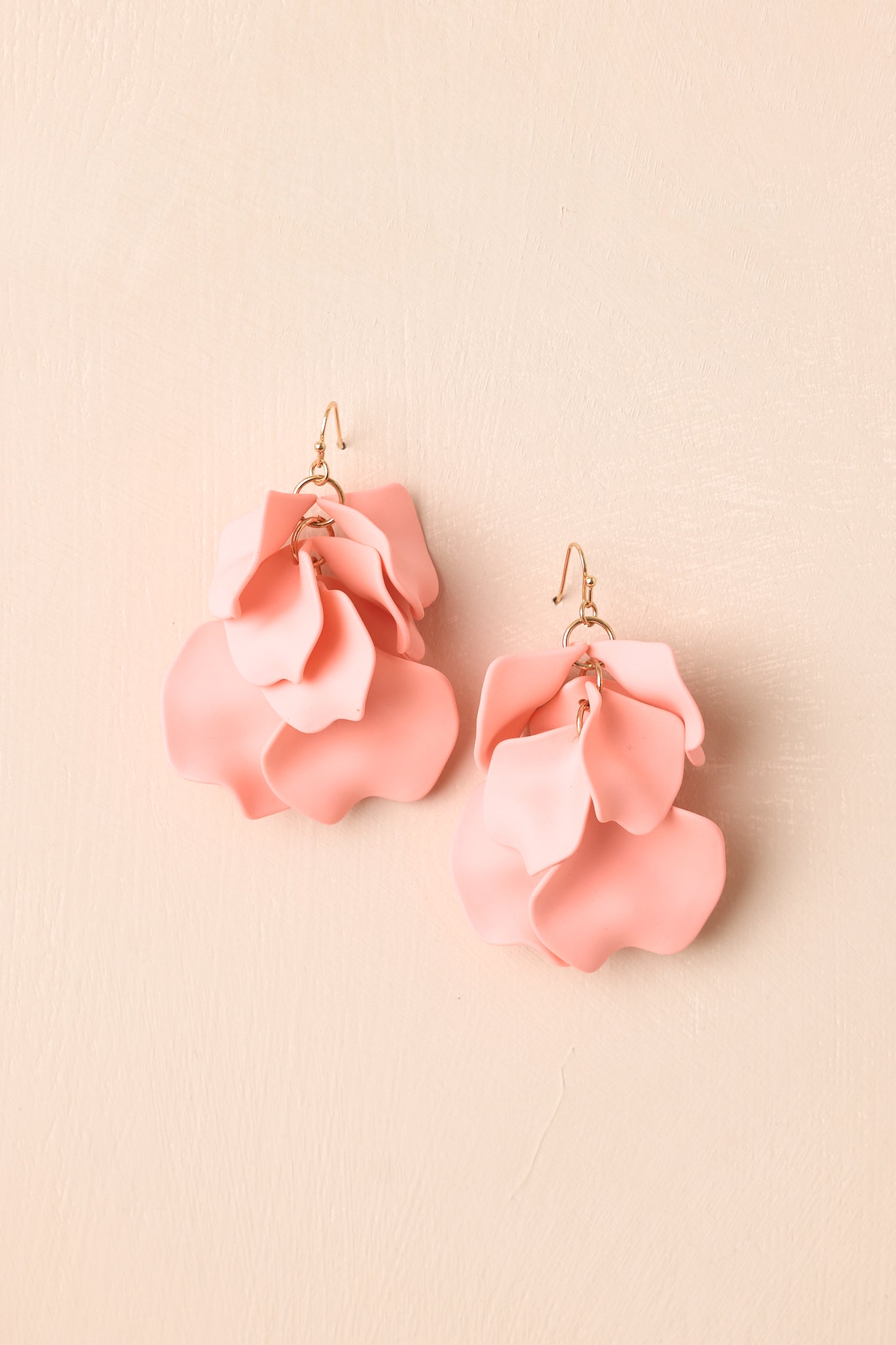 Front view of pink petal drop earrings displayed on beige background emphasizing cascading layered design.