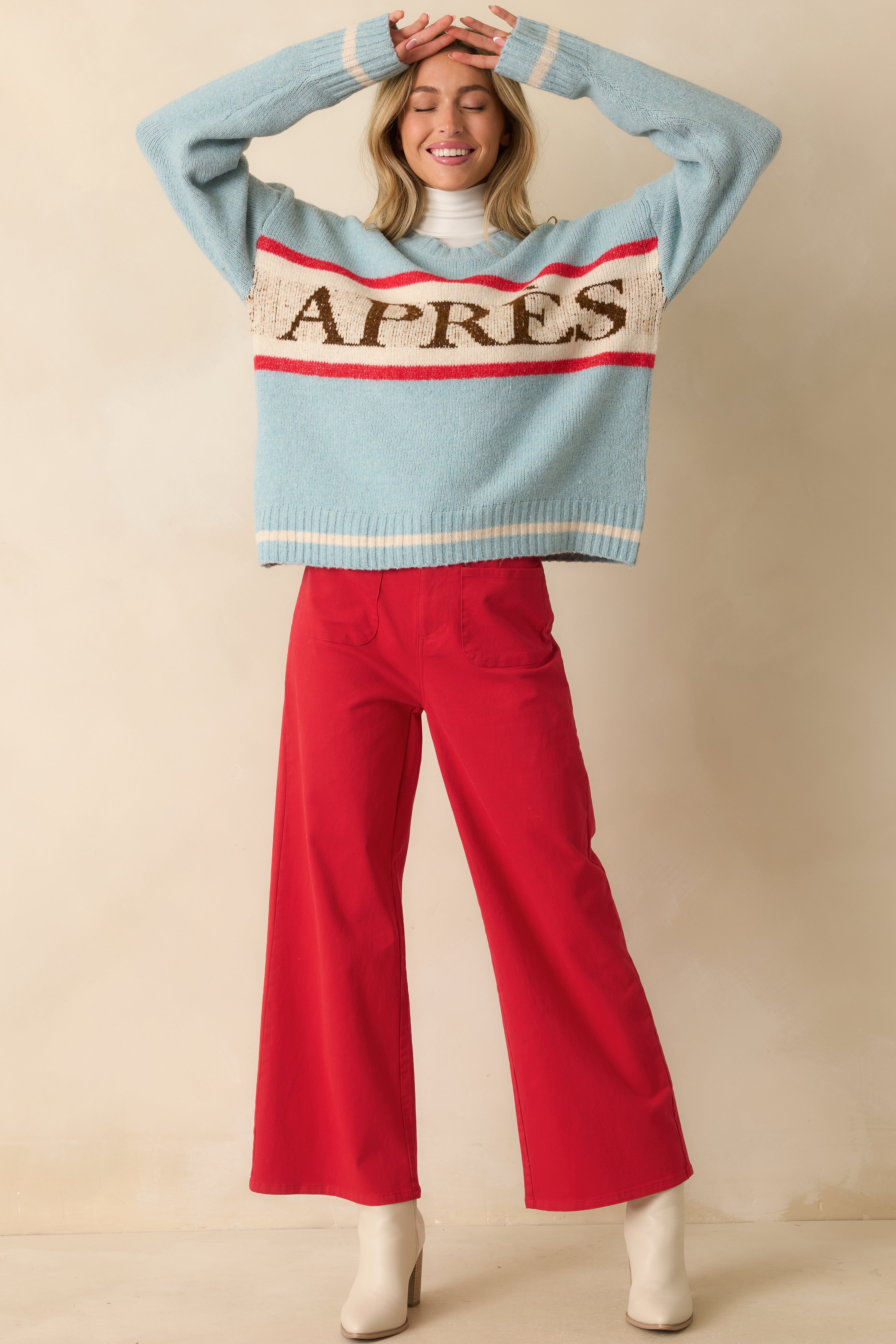 Front view of relaxed blue sweater featuring contrasting red and ivory stripes and cozy knit construction.