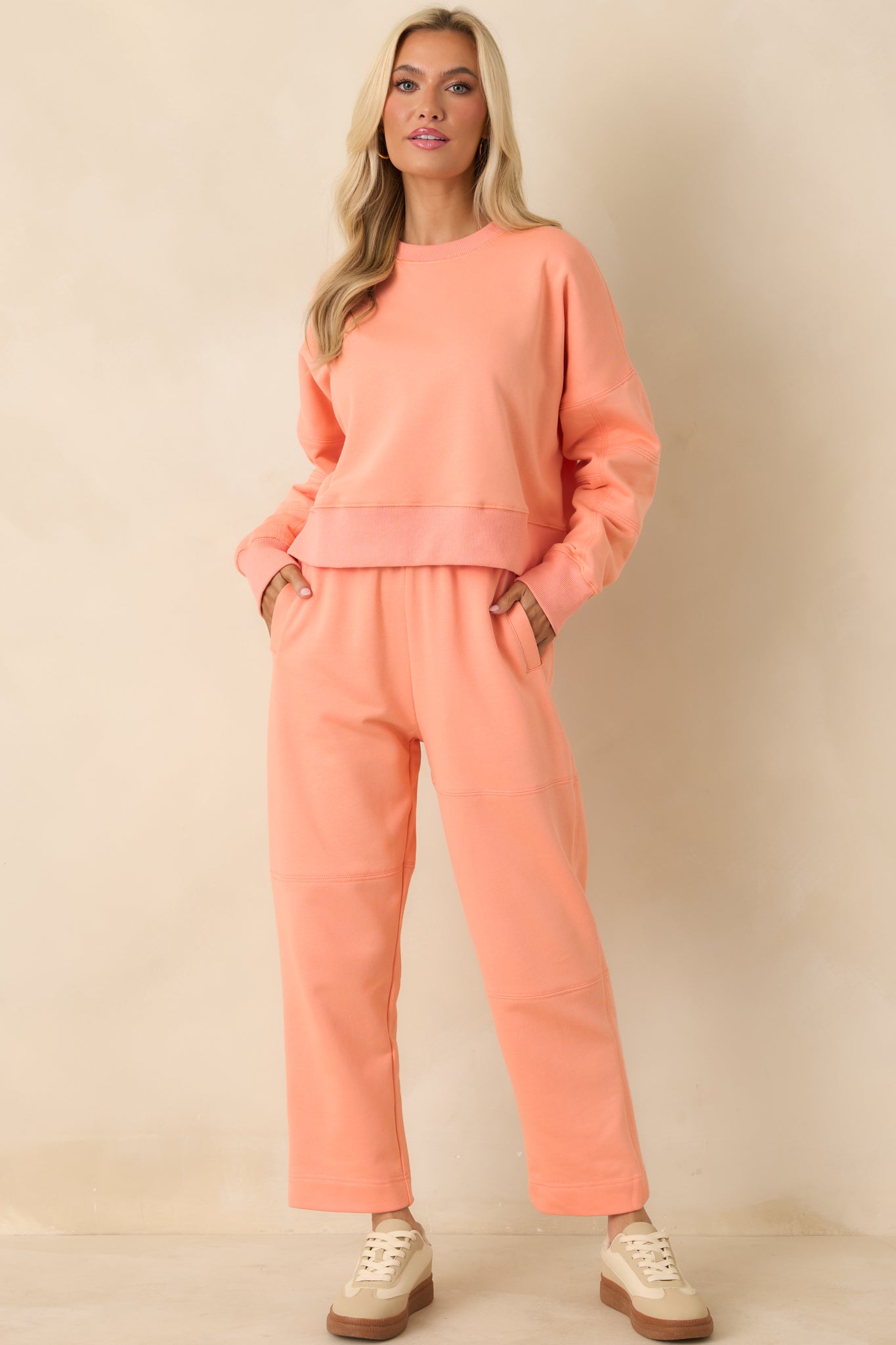 Front view of soft knit orange pants featuring side pockets and subtle tapered ankles.