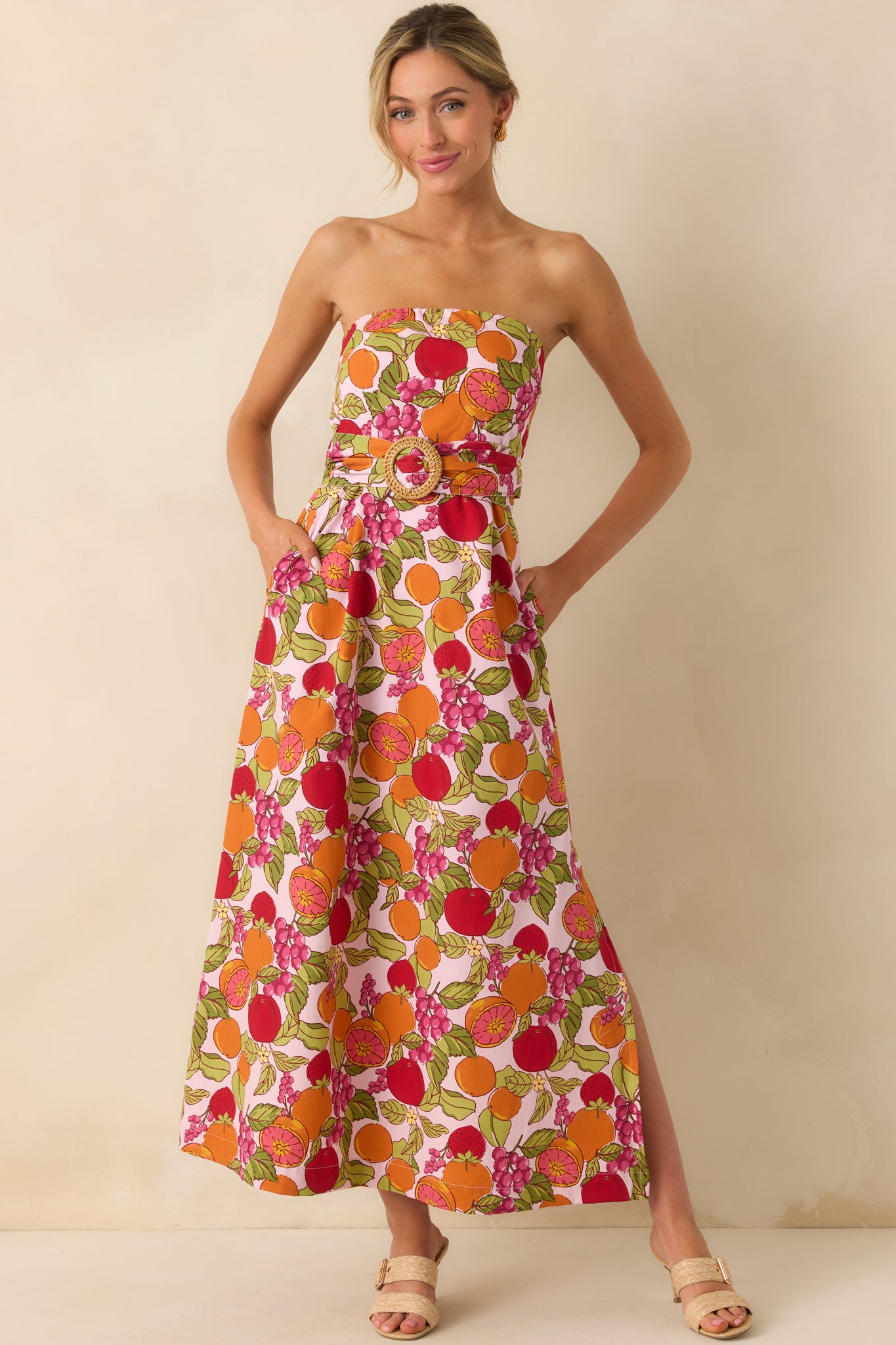 Front-facing view with hands in pockets, emphasizing the dress’s functional pockets and playful fruit print.