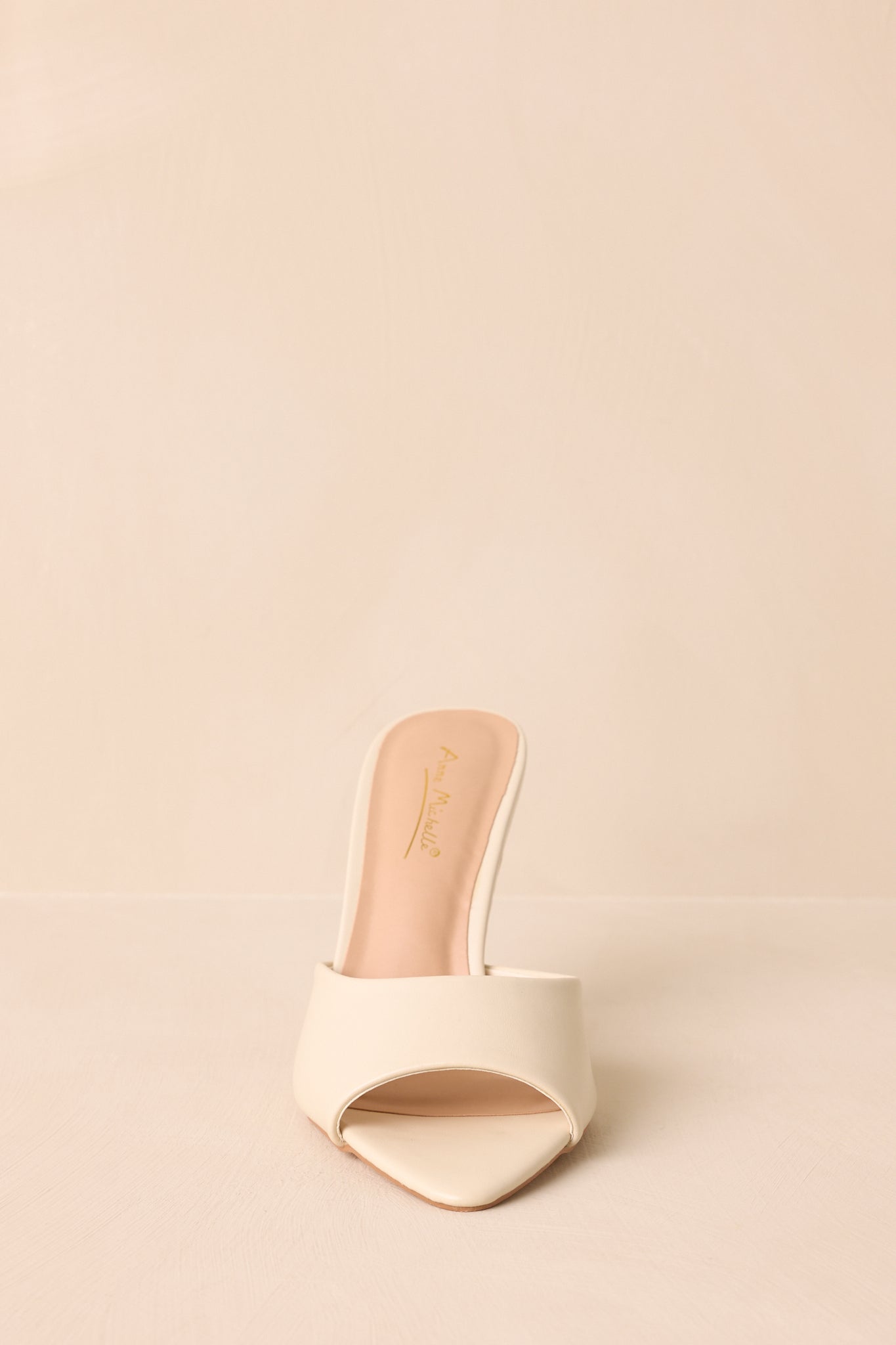Close front view of the ivory open-toe mule heels showing the smooth faux leather upper.