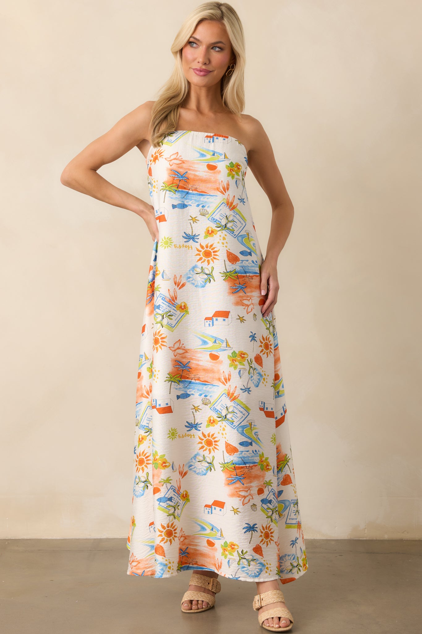 Front view of the strapless maxi dress featuring an orange multicolor tropical print and a floor-length silhouette.