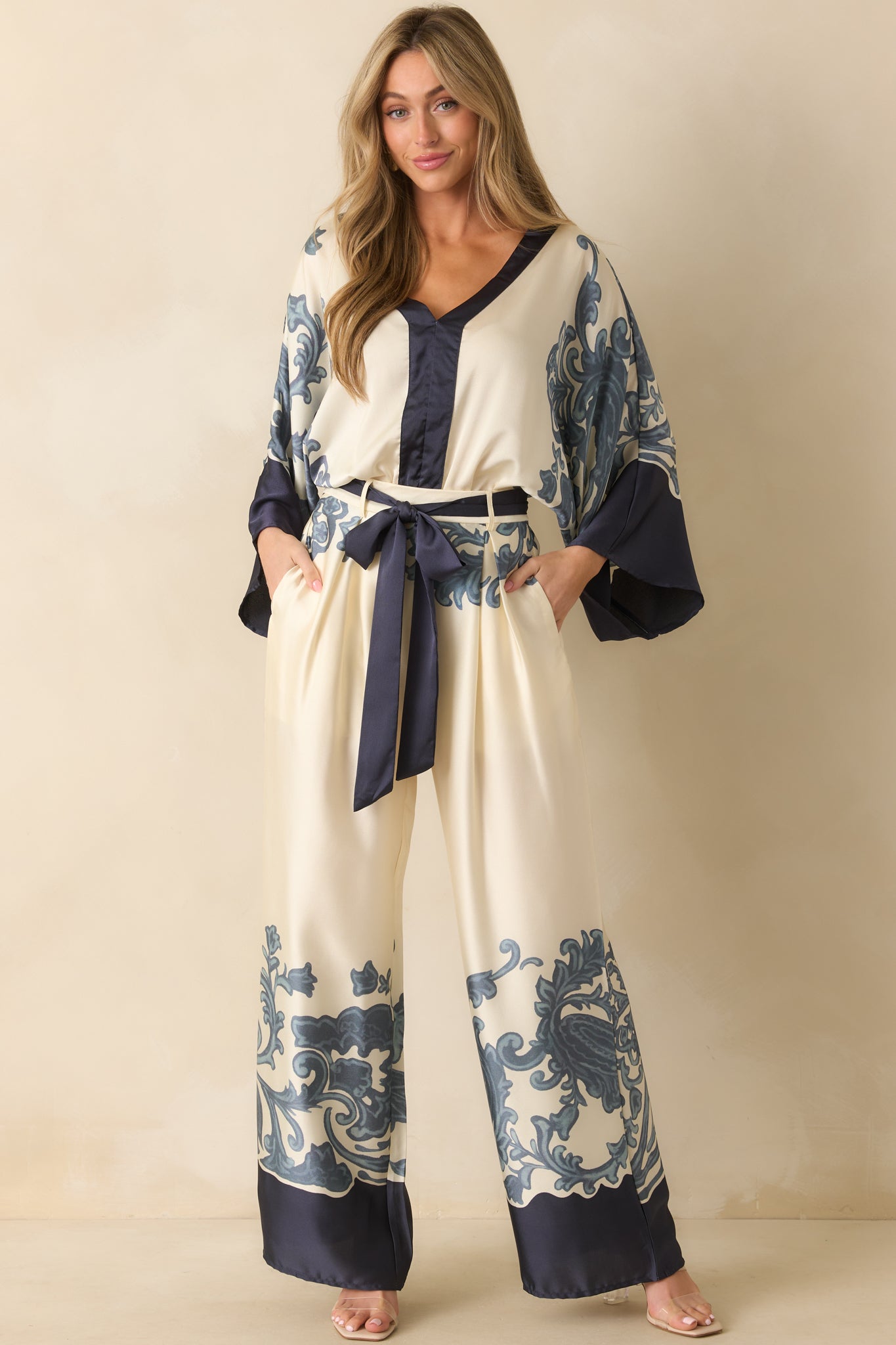 Front view of ivory wide-leg pants showing functional front pockets, belt loops, and optional navy self-tie sash.