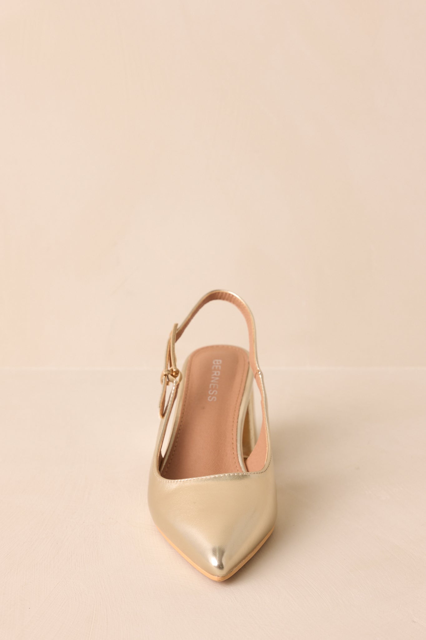 A front view emphasizing the pointed toe and shiny gold patent finish.