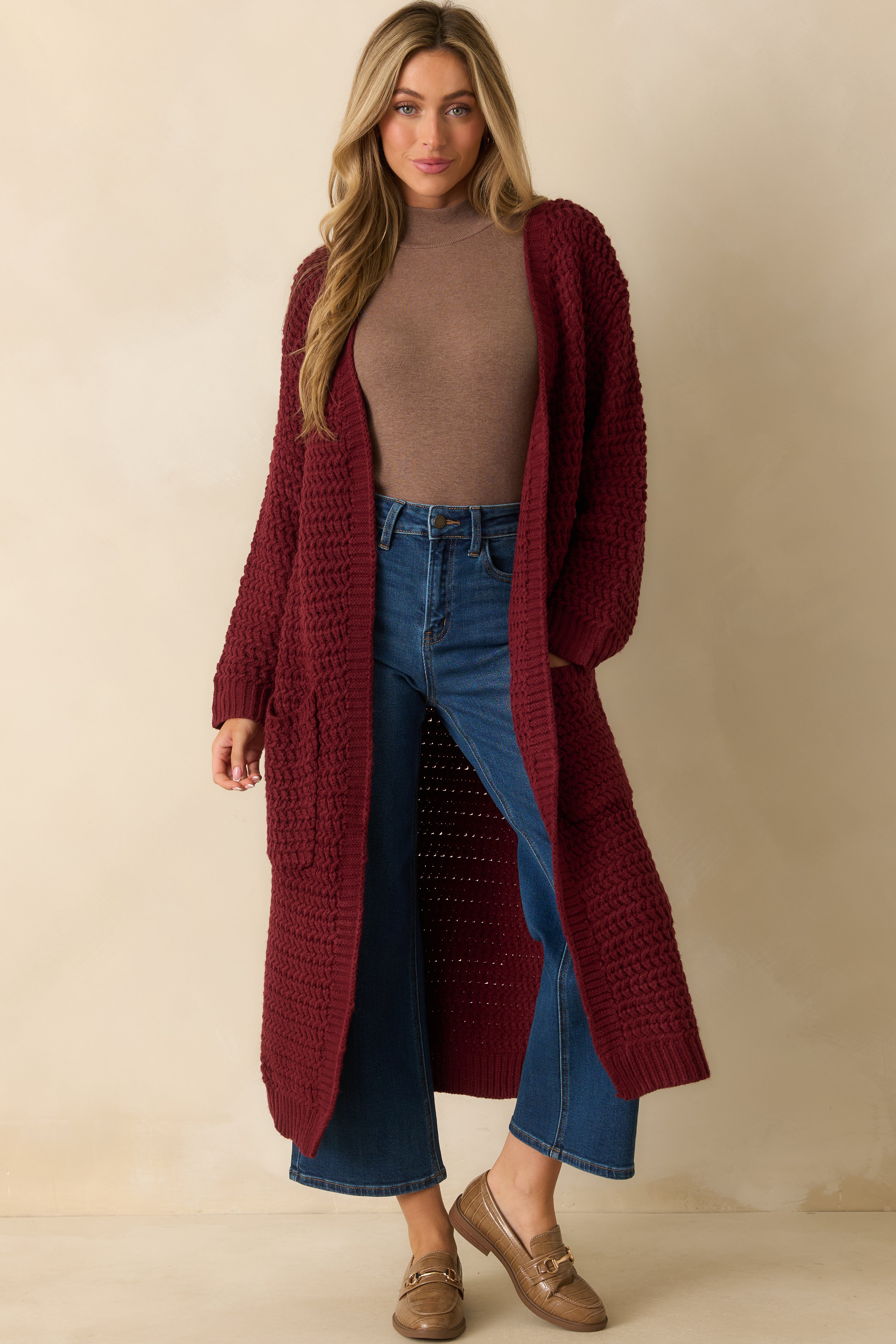 Front view of red knit duster cardigan featuring an open front and longline silhouette.