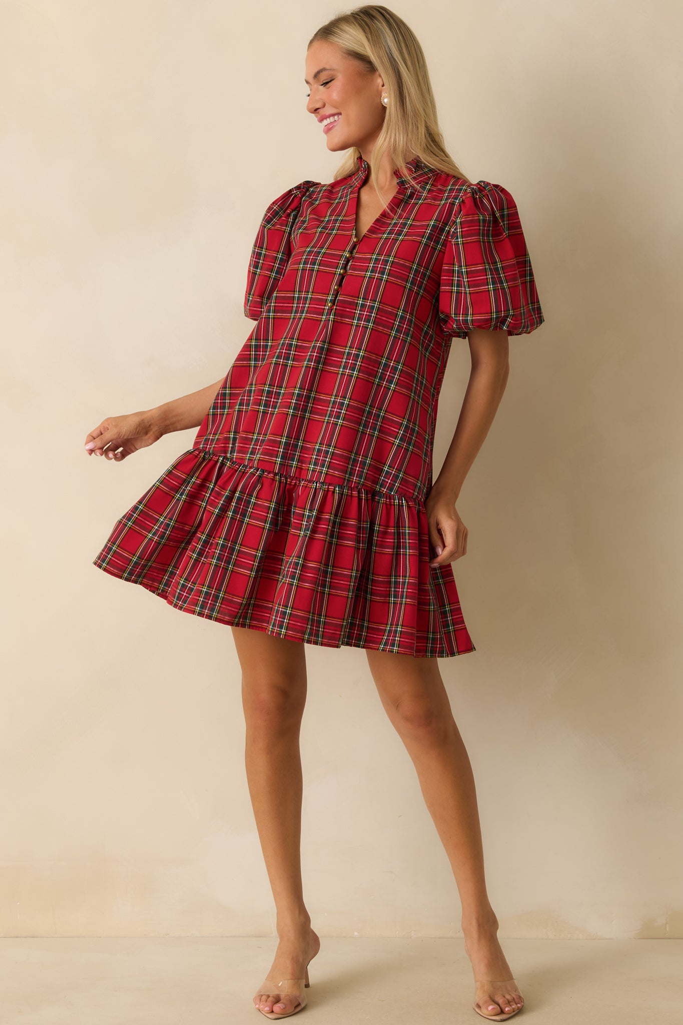 Front view of red plaid dress featuring relaxed fit, soft woven fabric, short puff sleeves, and mini-length ruffled hem.