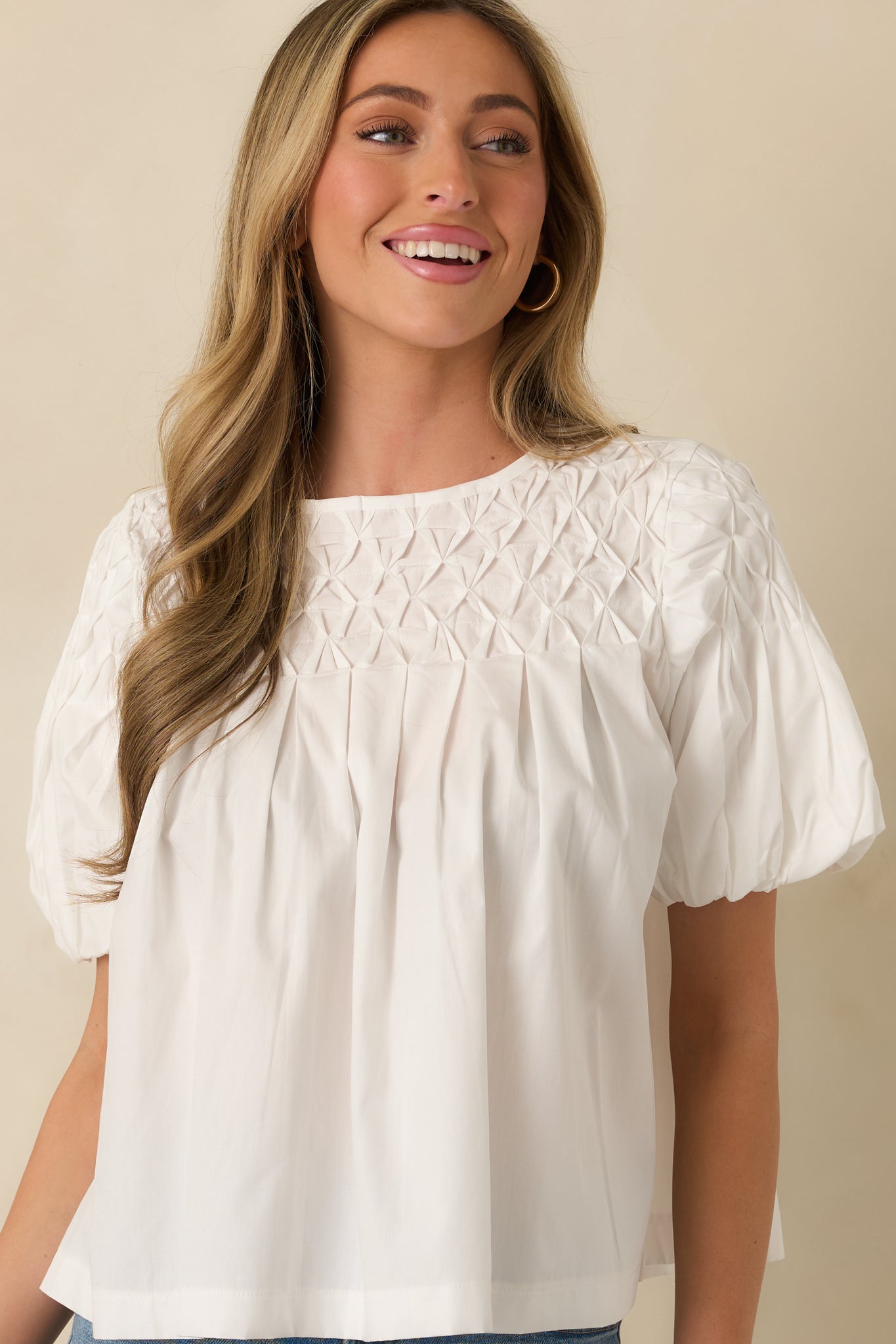 Close-in front view of the white top showing the gathered puff sleeves and structured smocked yoke.