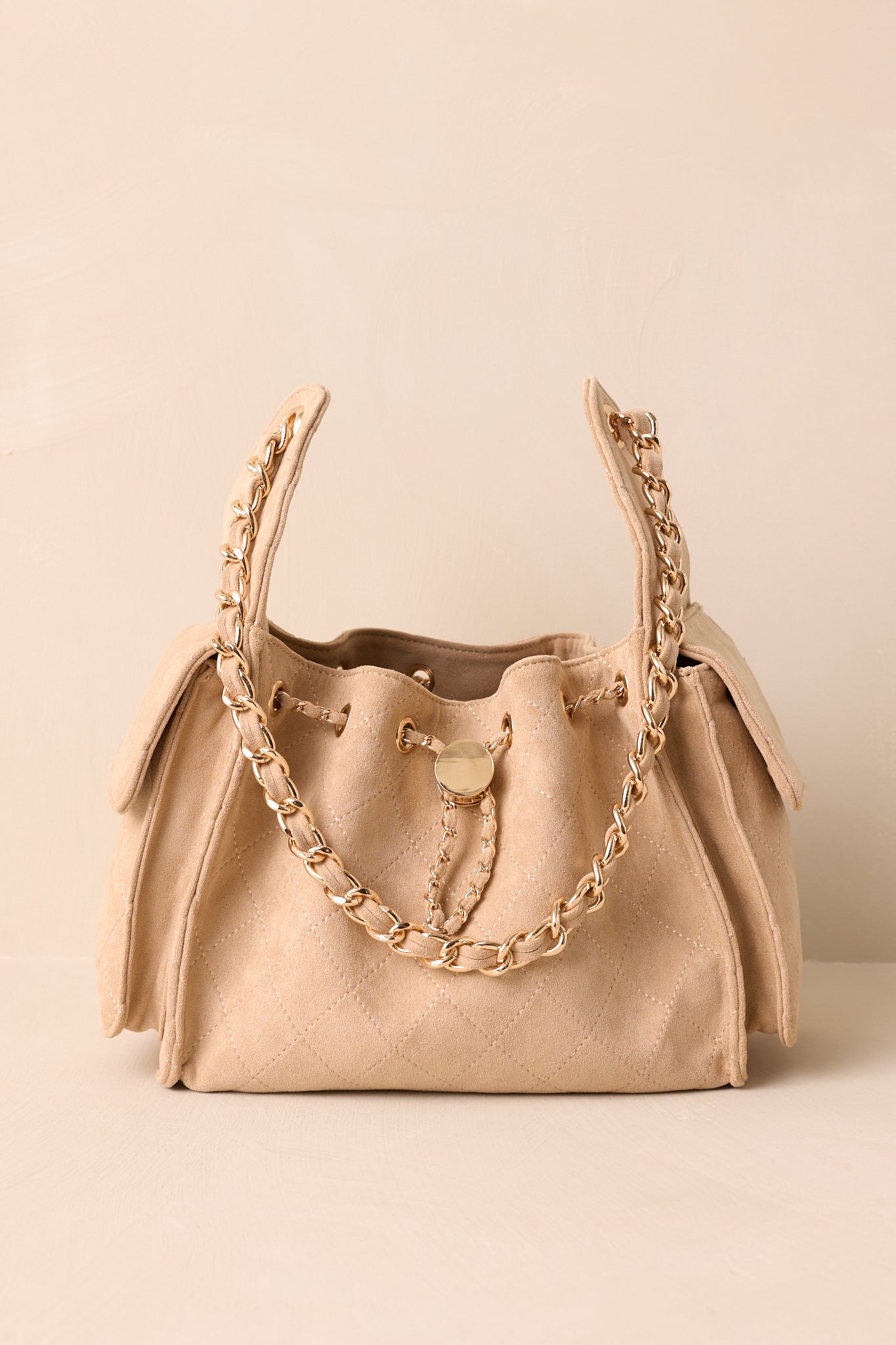 Front view of taupe quilted purse highlighting its structured shape, side pockets, and interlaced gold chain strap.