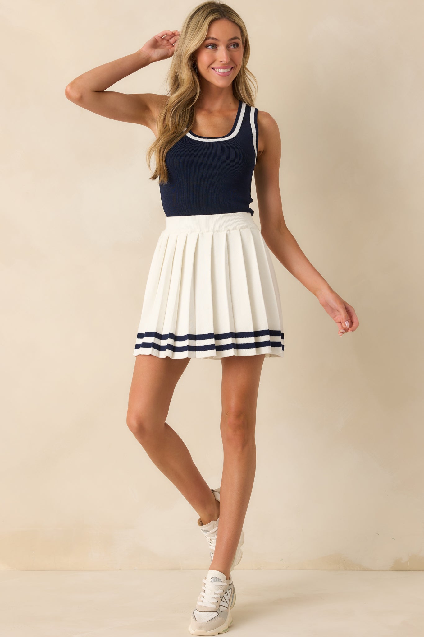 Full body front view of the white skirt showing the pleated design and navy striped hem.