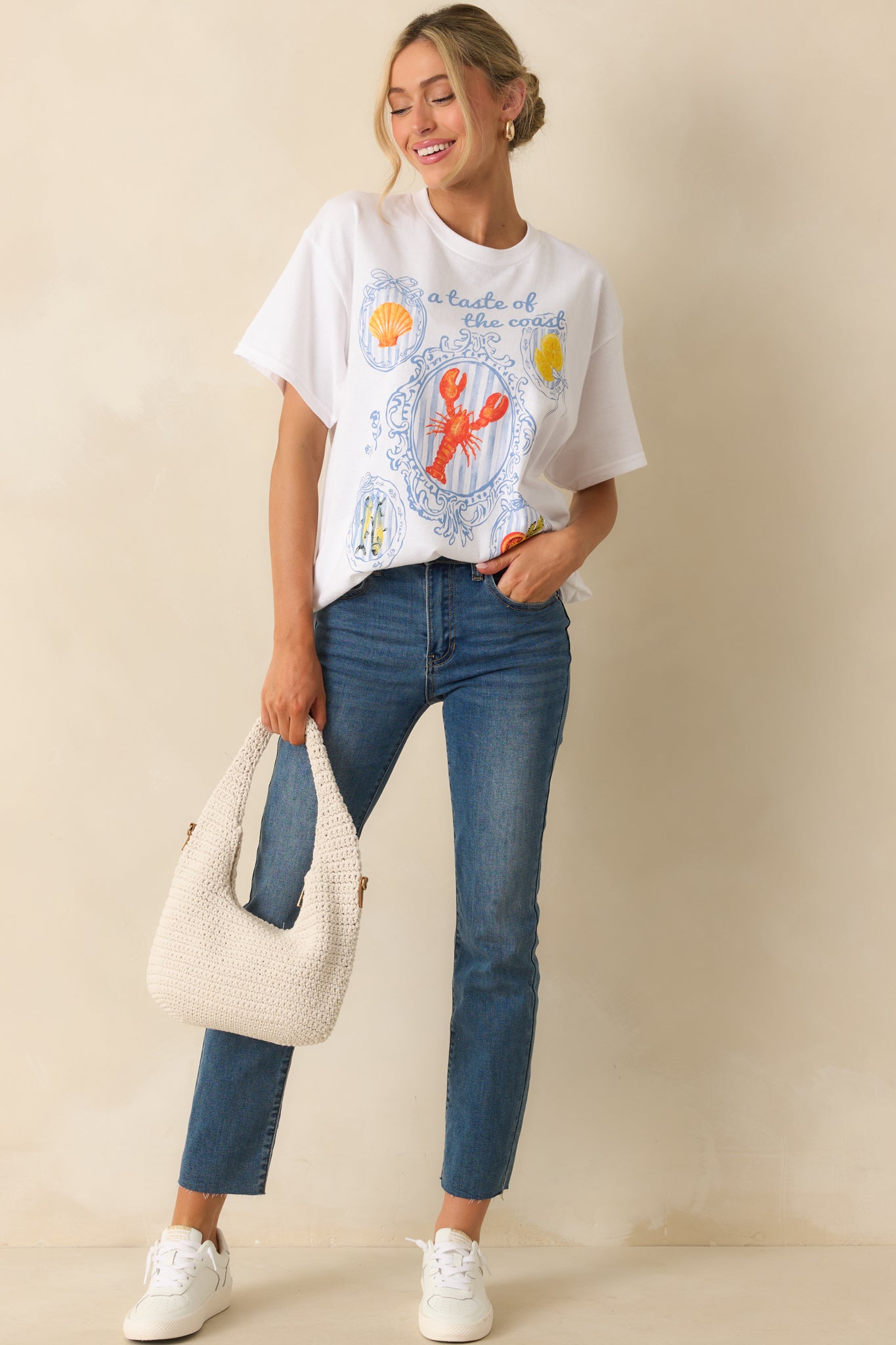 White short-sleeve tee displayed from the front with visible relaxed fit and detailed multicolor coastal design.