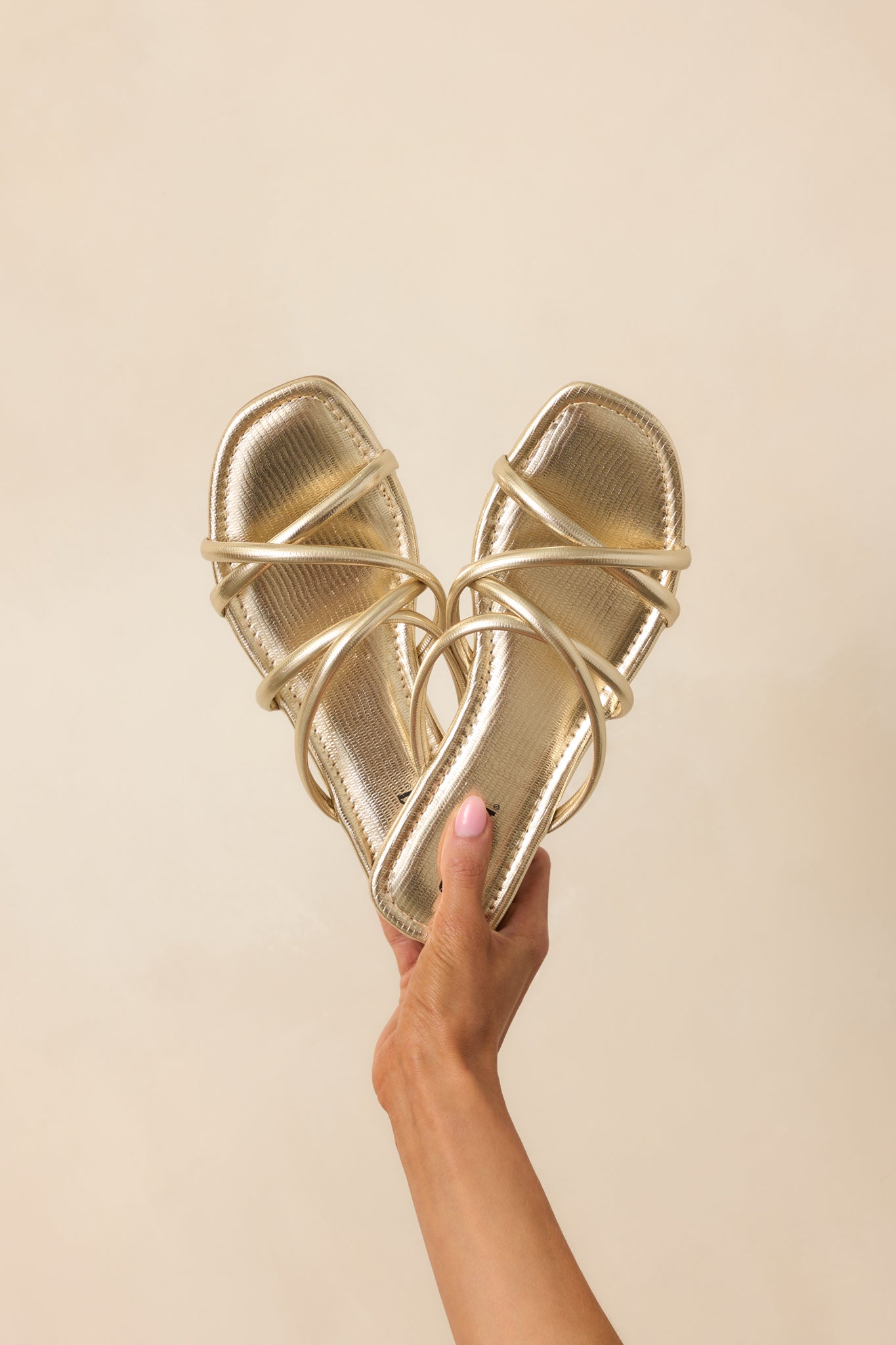 A close-up frontal shot of the sandals, highlighting the metallic gold finish on the straps along with the texture and reflective surface.