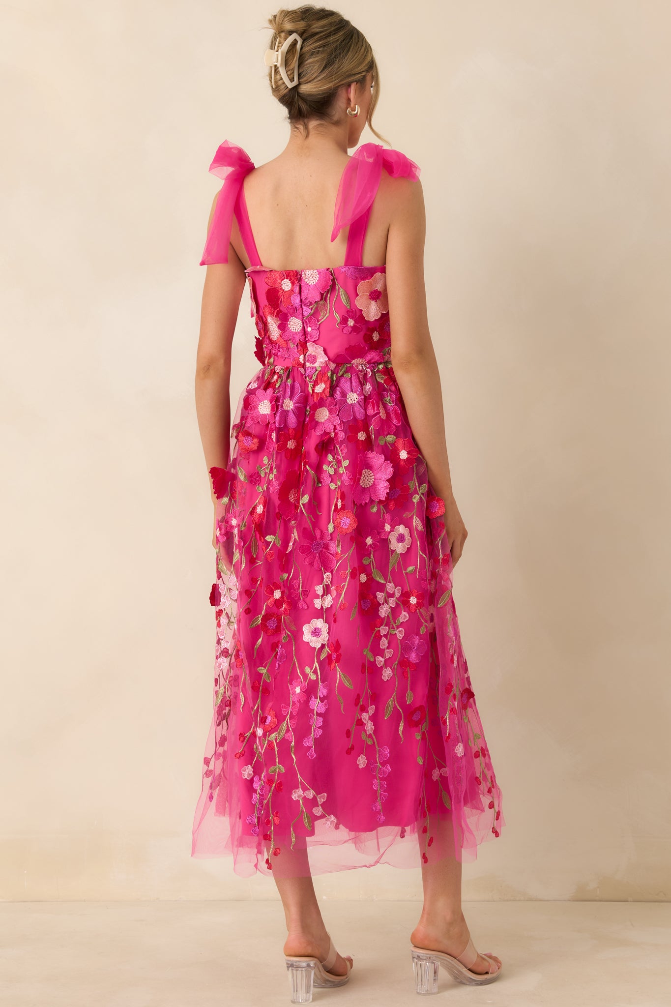 Back view of the fuchsia pink dress highlighting the sheer straps and floral appliqué continuation across the back.